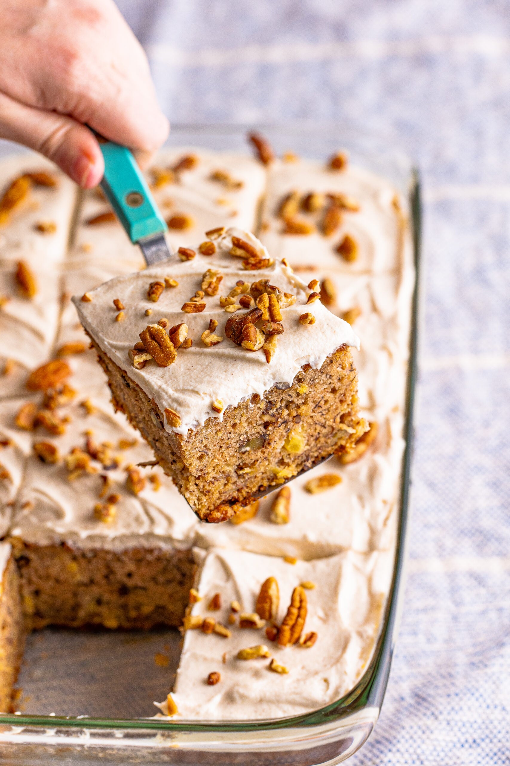 Hummingbird Cake in a clear baking dish with a slice being lifted up on a spatula