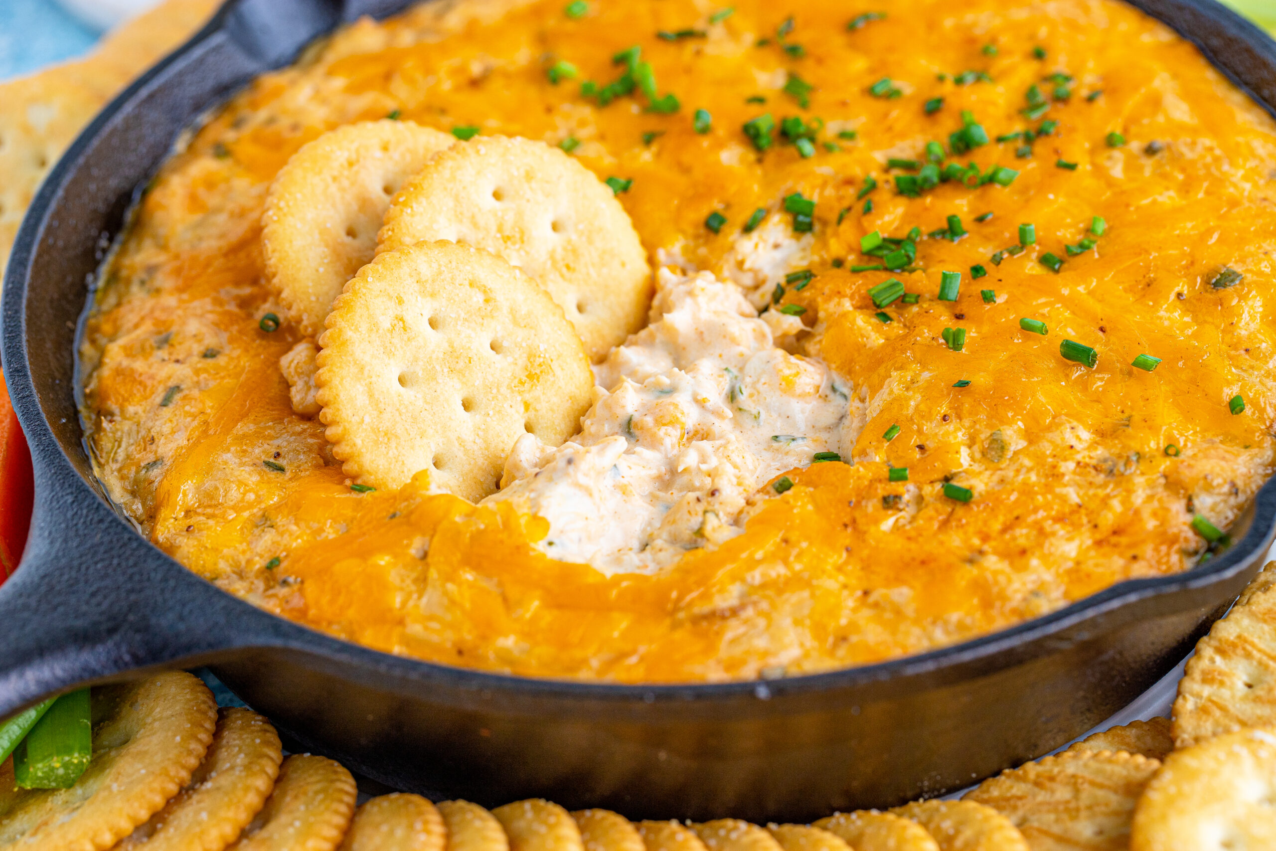 Front view of Crab Dip Recipe in a cast iron skillet served with crackers and vegetables.