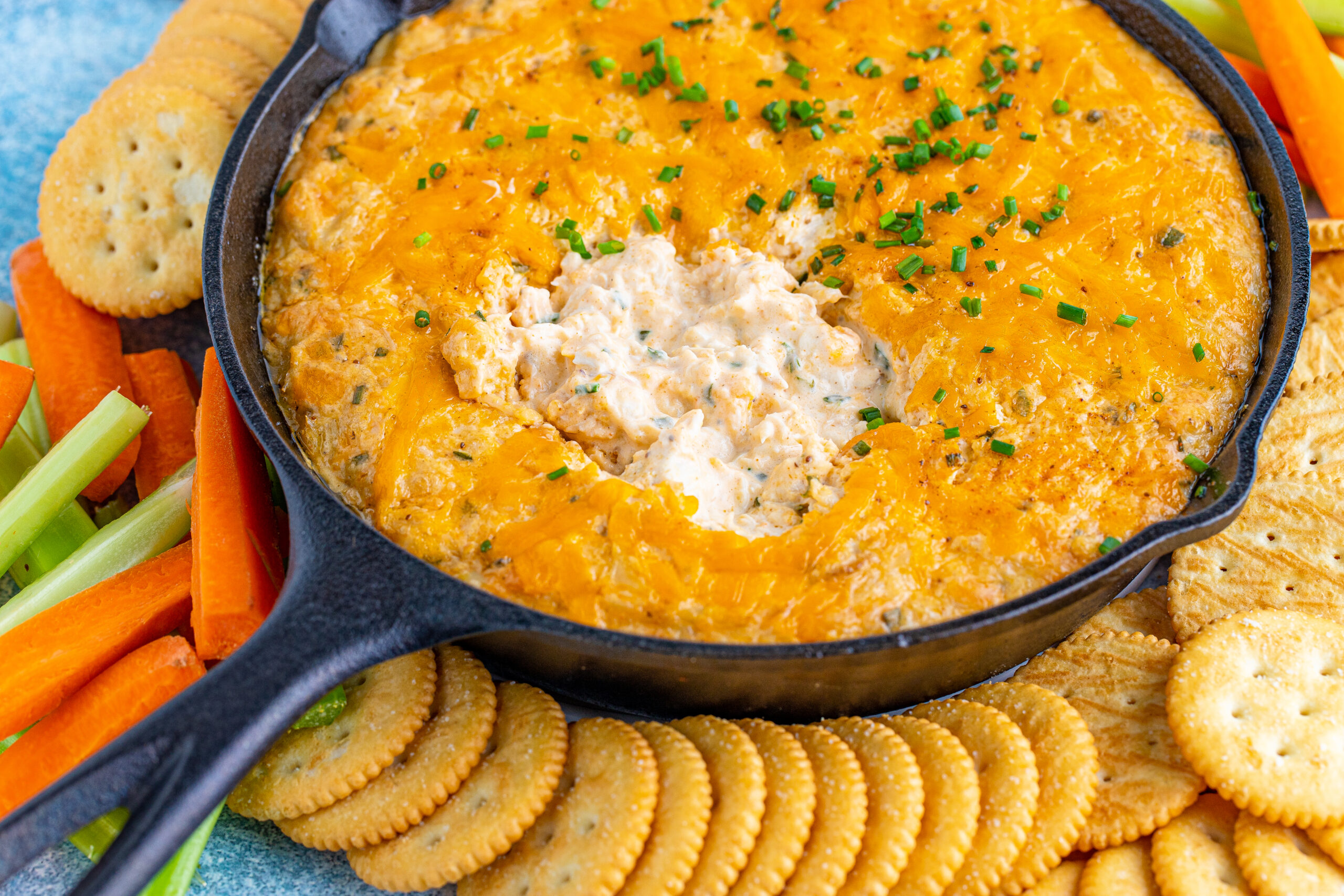 Front view of Crab Dip Recipe in a cast iron skillet served with crackers and vegetables.