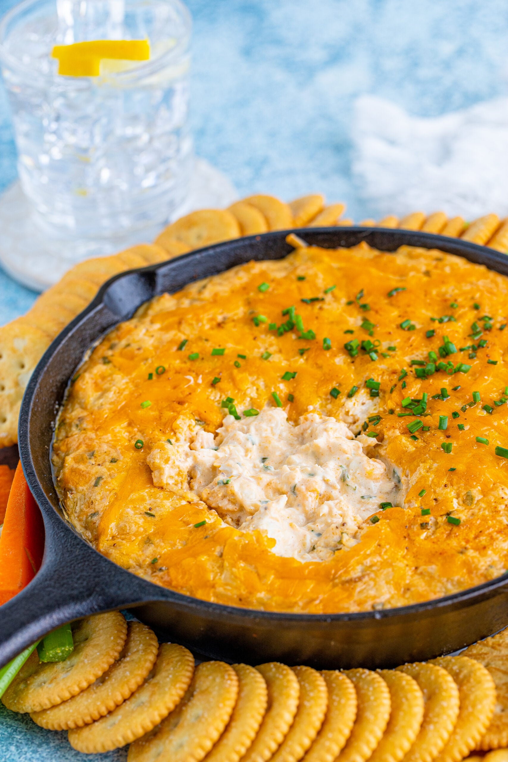 Front view of Crab Dip Recipe in a cast iron skillet served with crackers and vegetables.