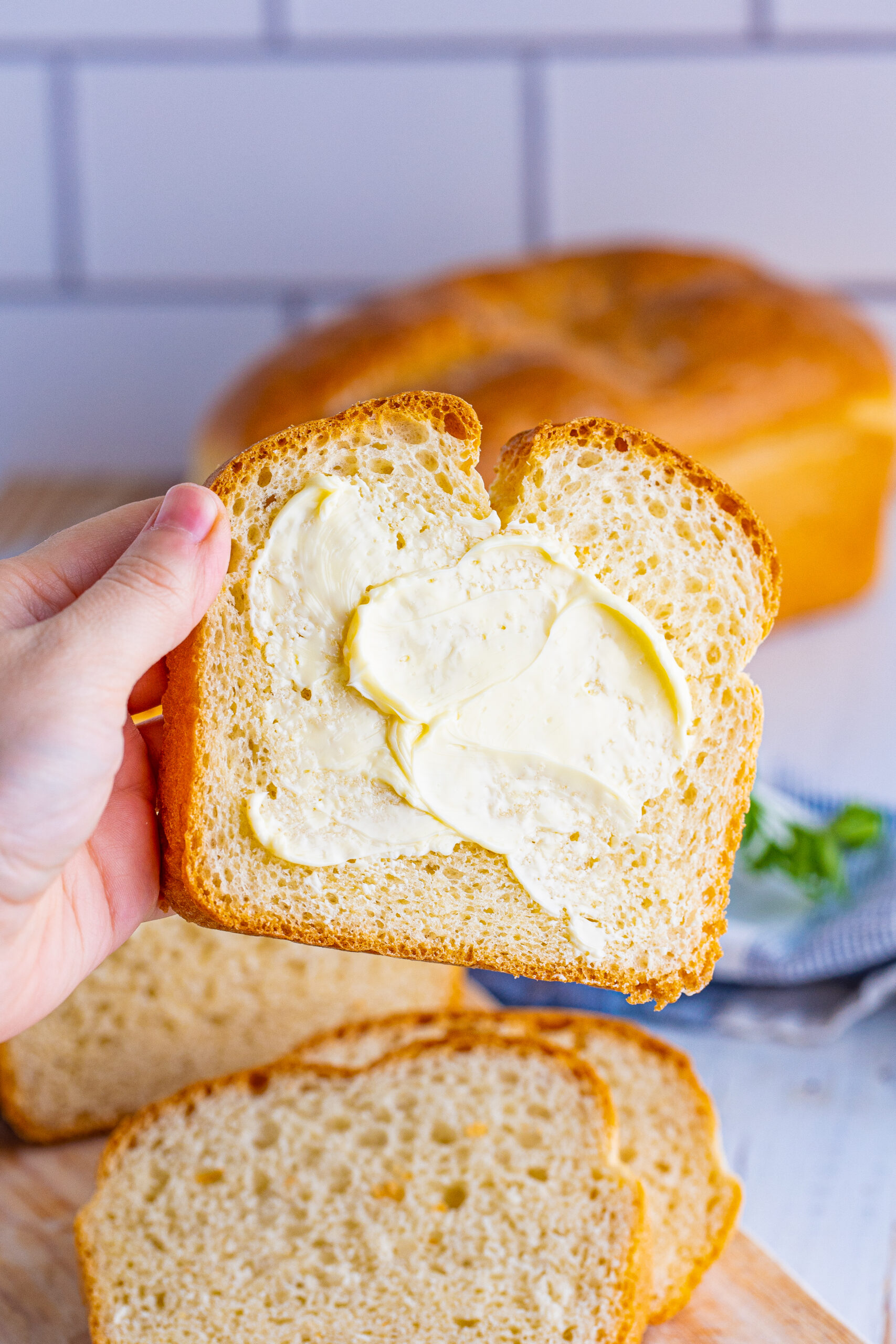 Front view of a slice of White Bread that is buttered.