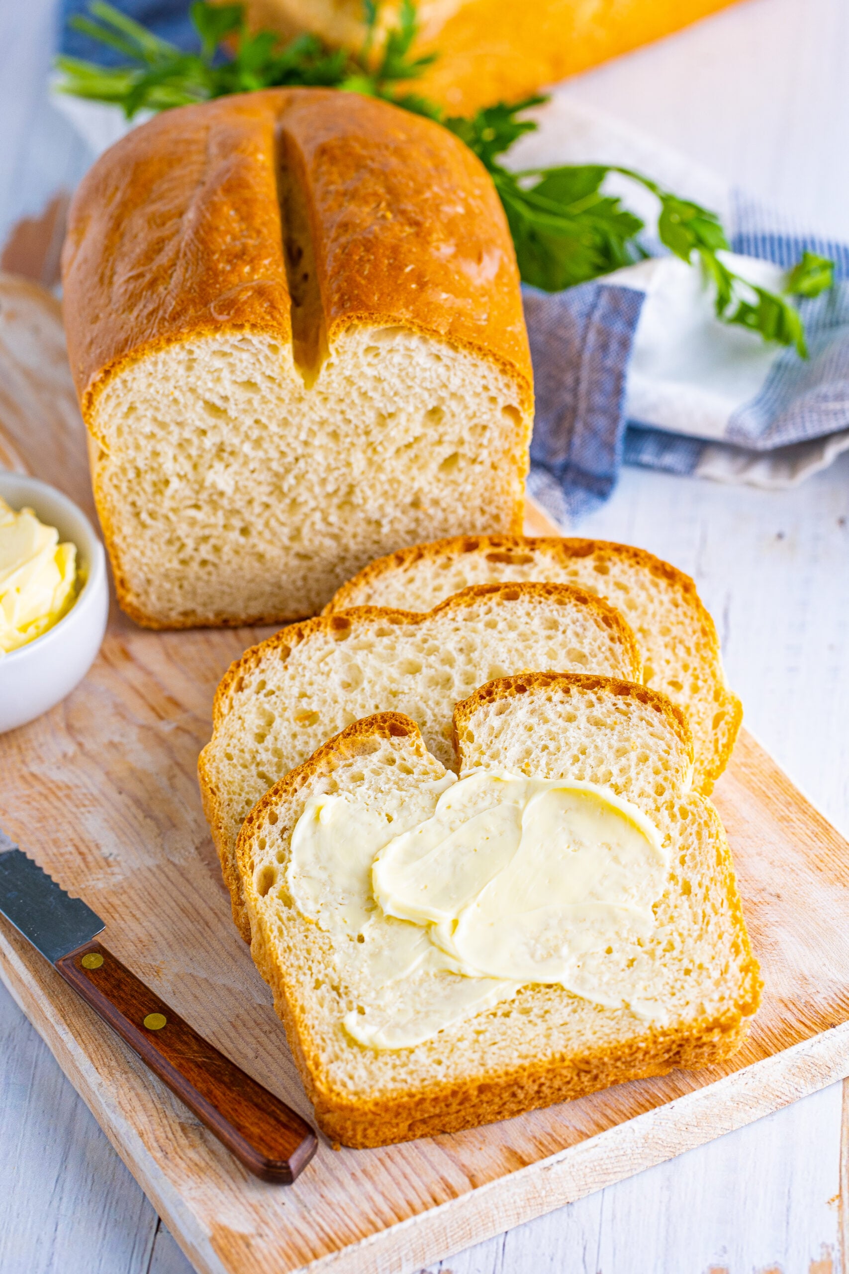 Front view of three slices of White Bread with butter spread onto the top slice.