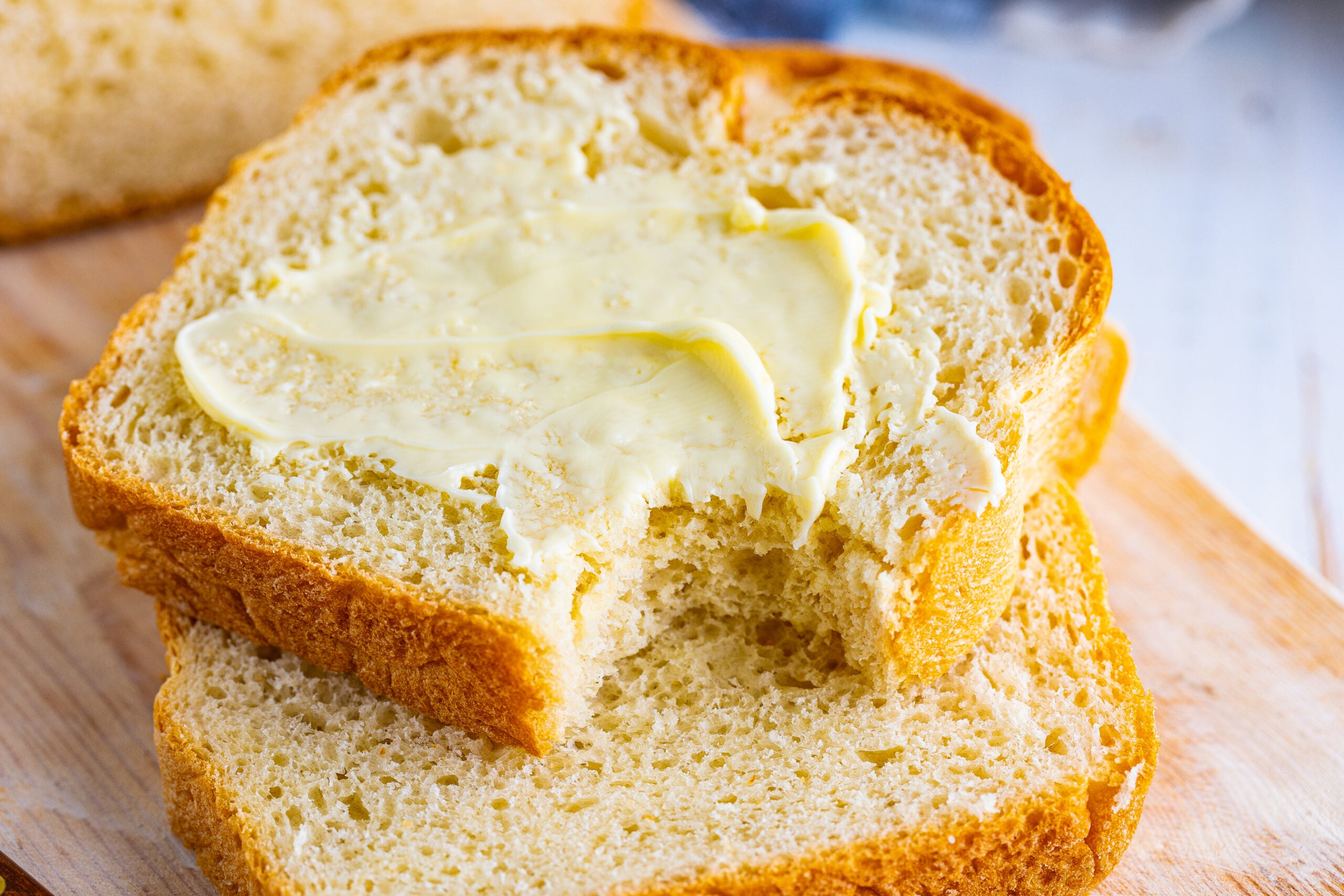 Front view of two slices of White bread stacked with the top slice buttered.
