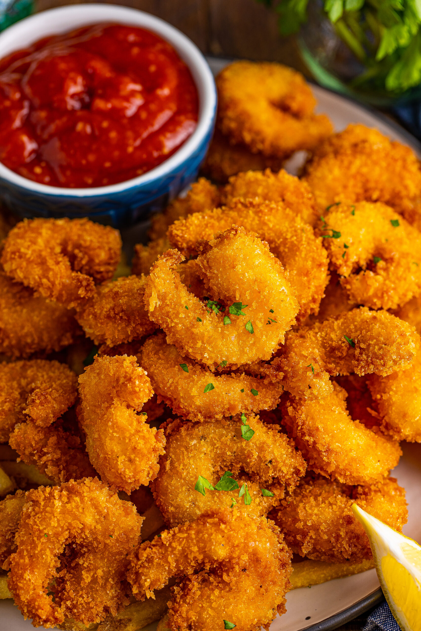 overhead view of Panko Fried Shrimp on a dish served with cocktail sauce and lemon wedges.