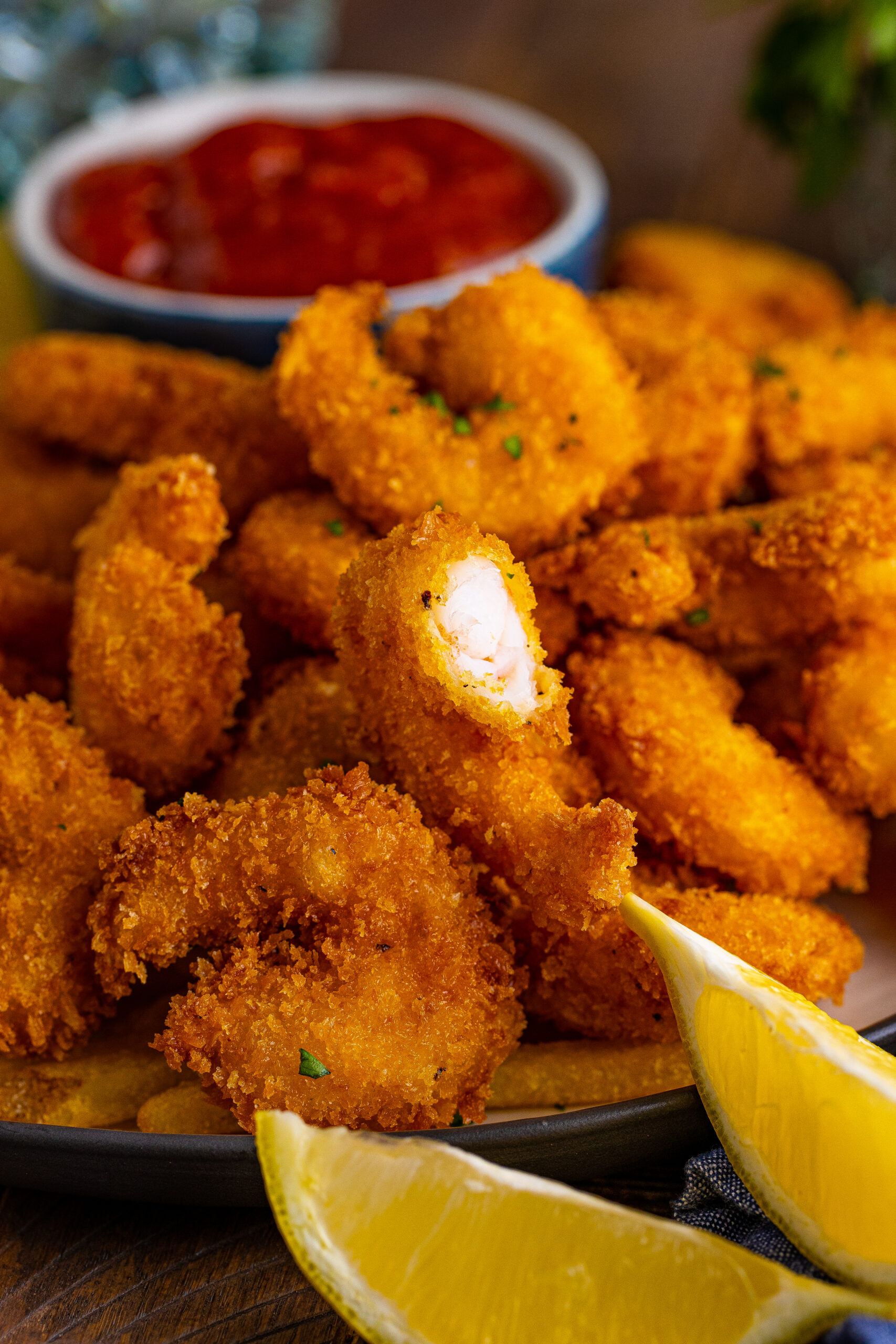 Front view of Panko Fried Shrimp on a dish served with french fries, cocktail sauce and lemon wedges.