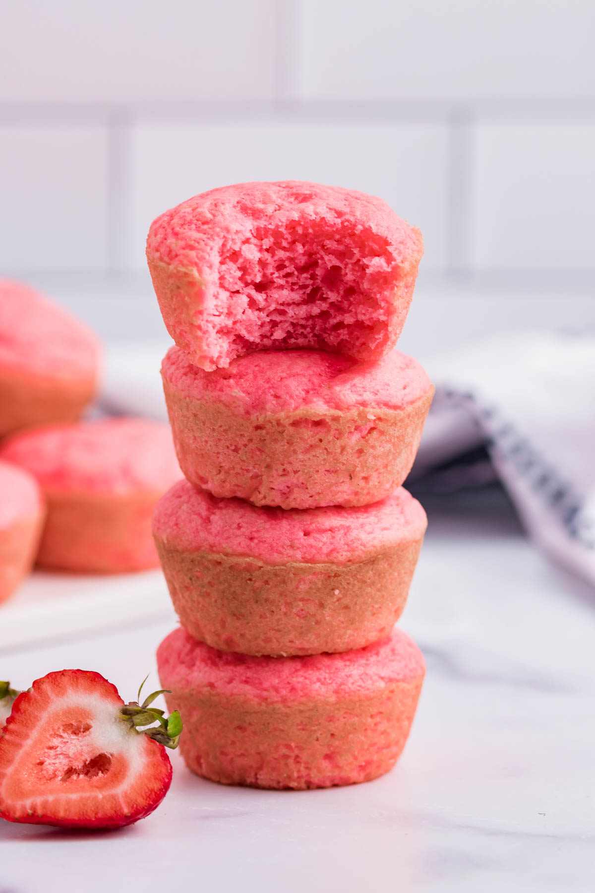 Front view of four Weight Watchers Strawberry Muffins stacked with a bite removed from the top muffin.