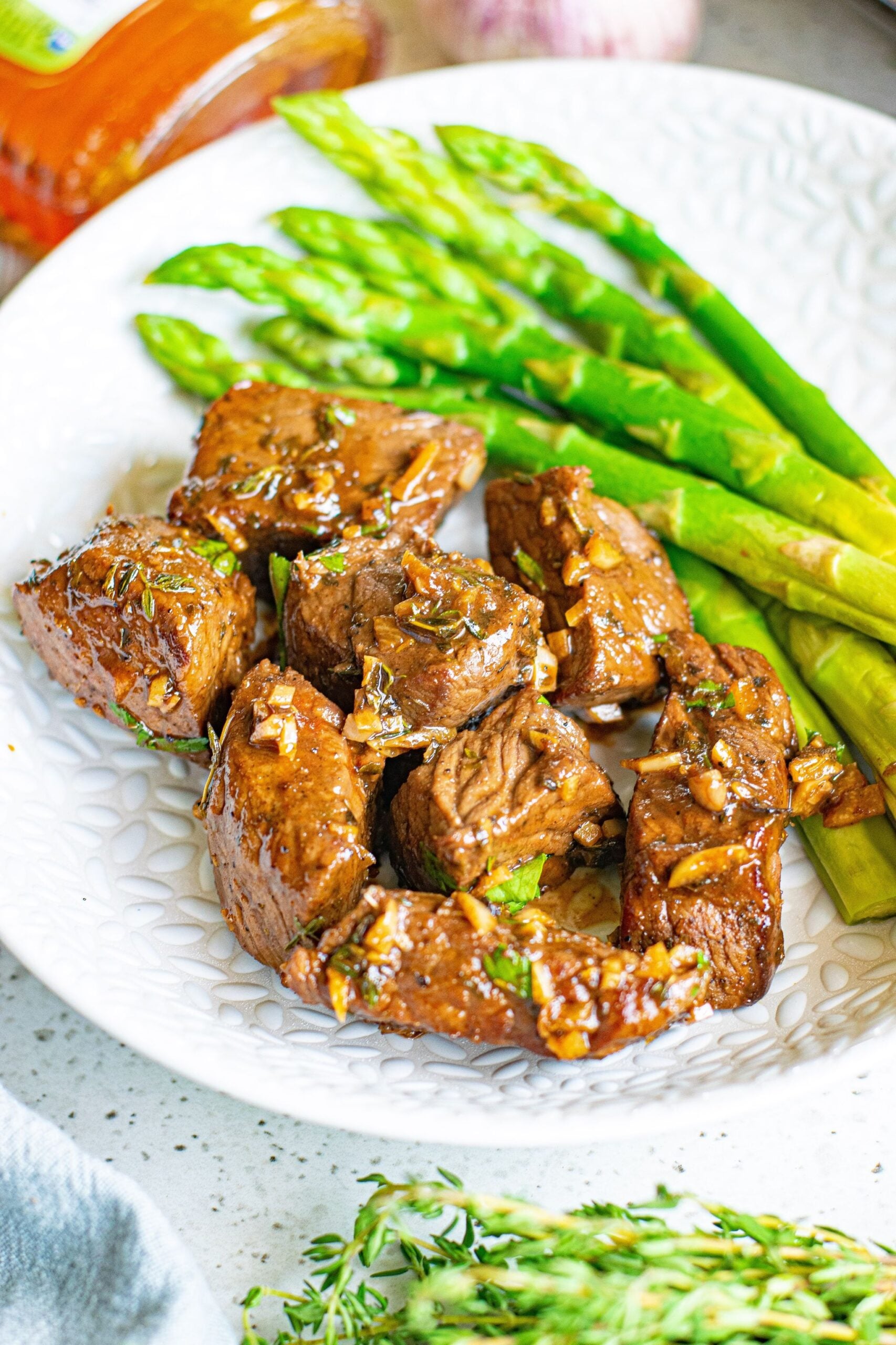 Front view of Garlic Honey Steak Bites served on a white dish with asparagus.
