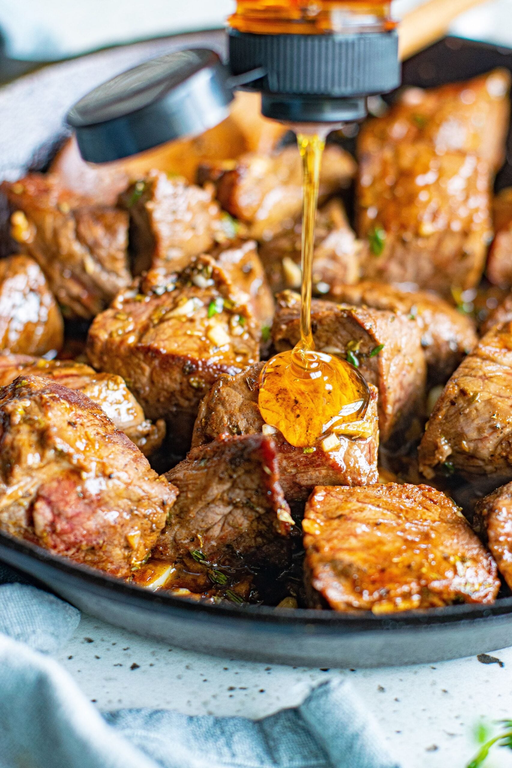 Close up view of honey being drizzled onto Garlic Honey Steak Bites.
