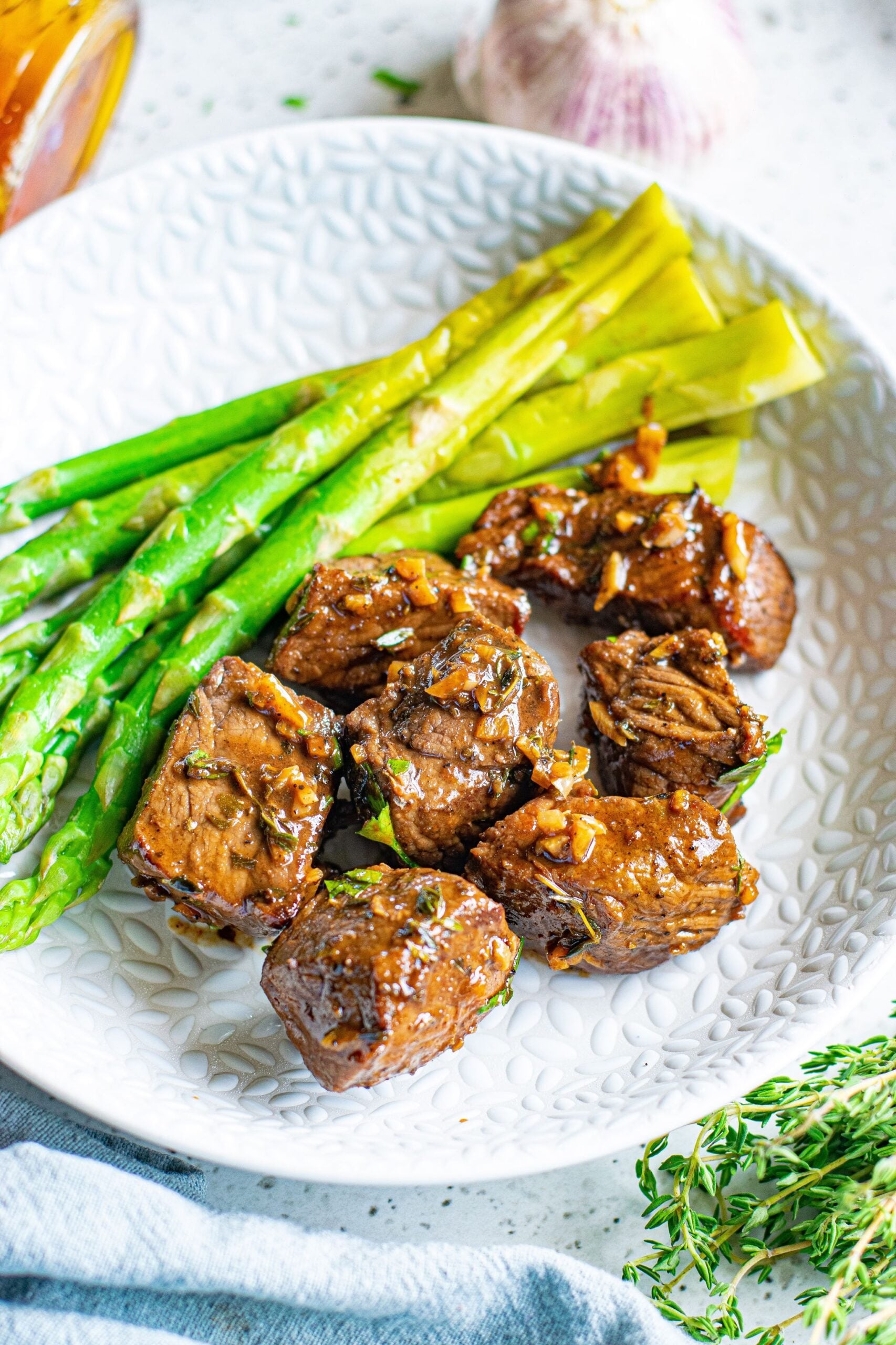 Front view of Garlic Honey Steak Bites served on a white dish with asparagus.