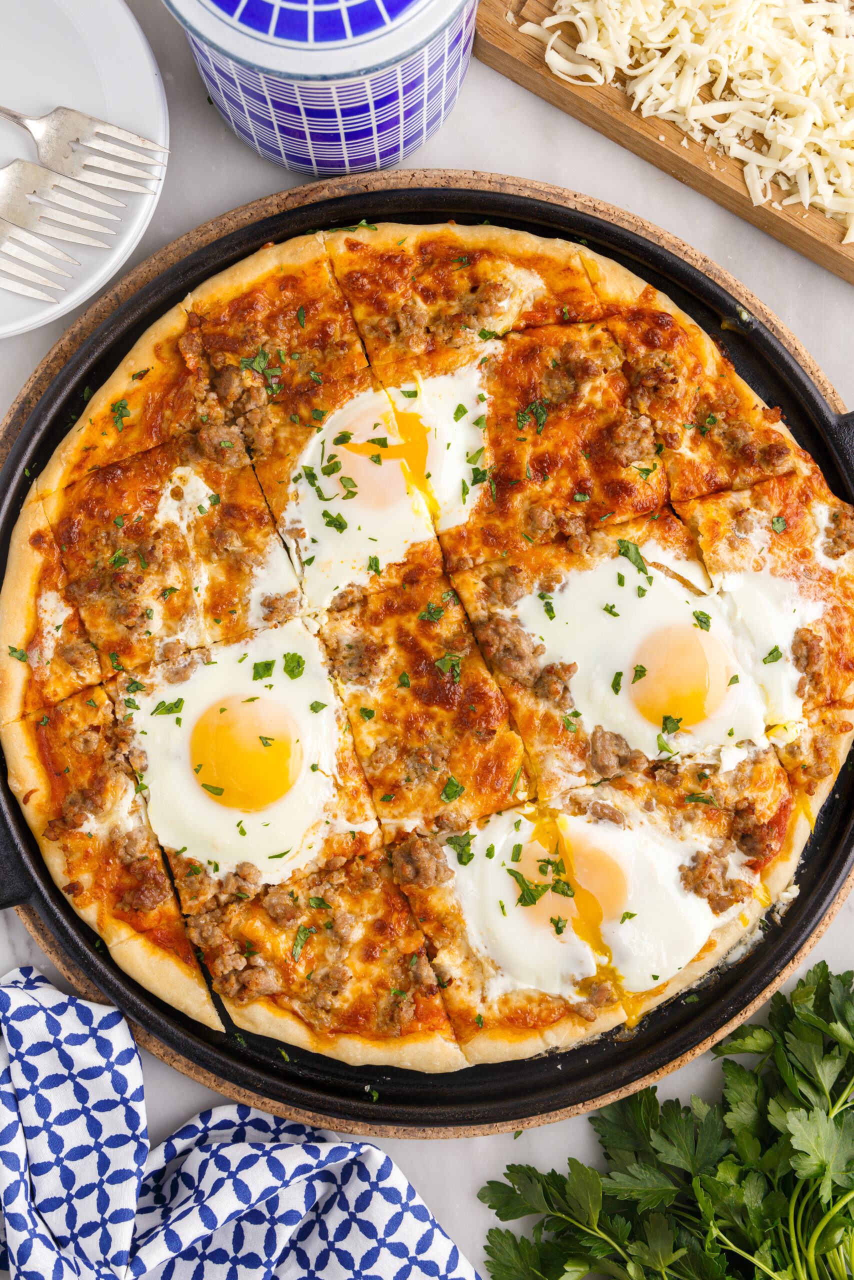 Overhead view of Breakfast Pizza on a black pizza dish cut into square slices.