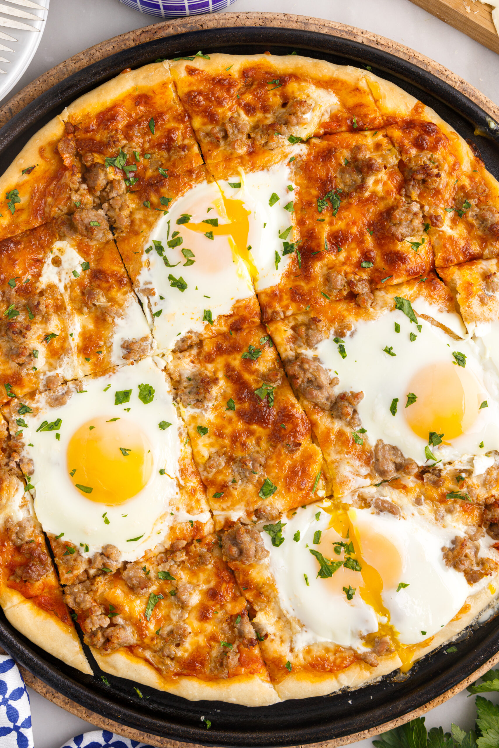Overhead view of Breakfast Pizza on a black pizza dish cut into square slices.