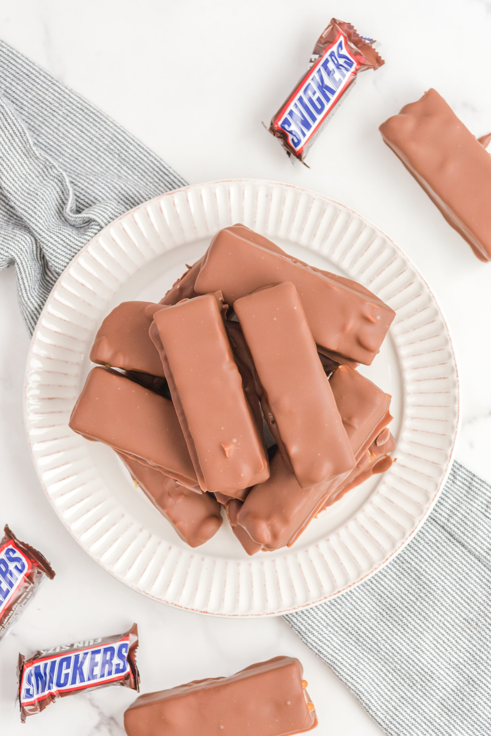 Overhead view of Homemade Snickers Bars stacked on a white plate.
