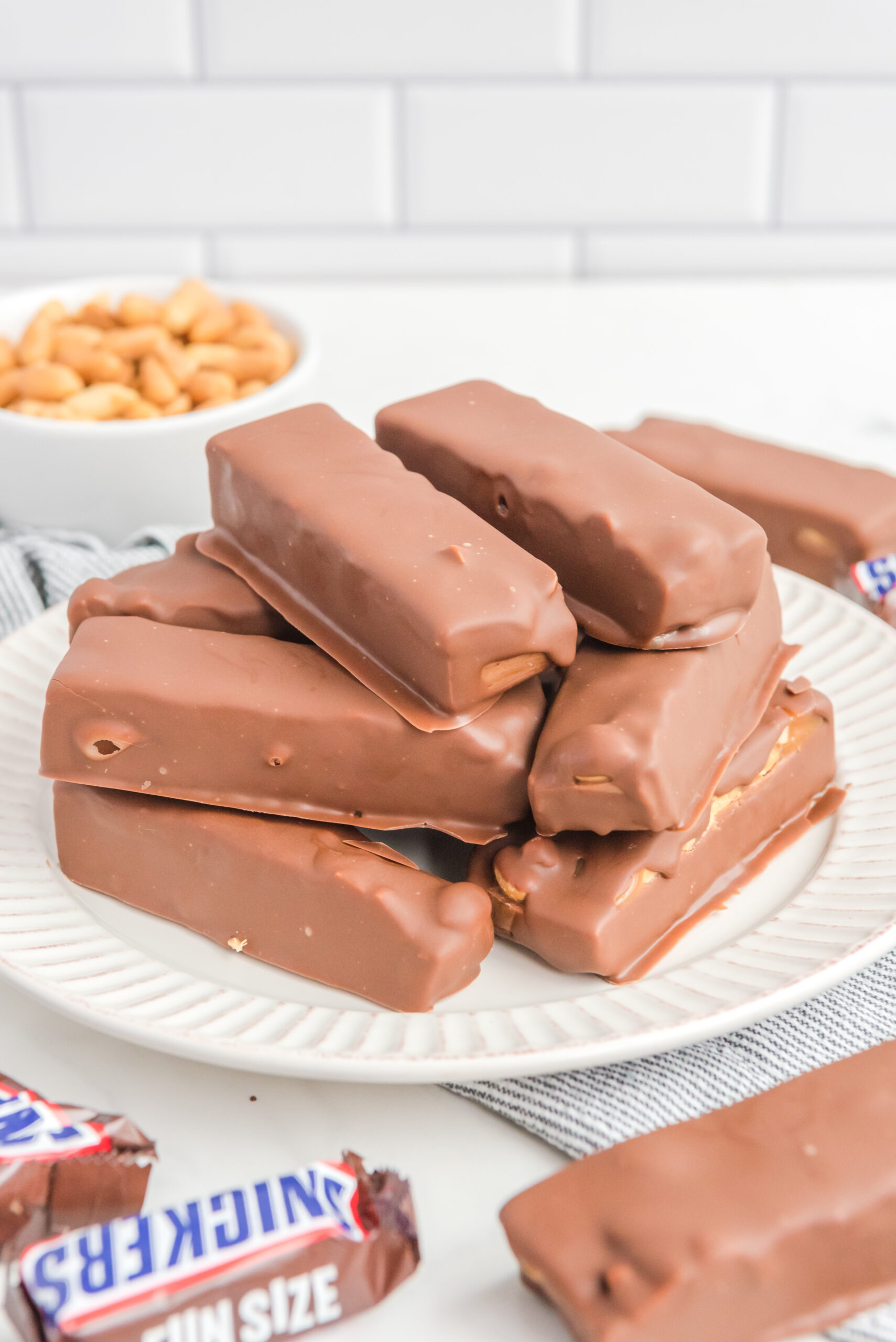 Front view of Homemade Snickers Bars stacked on a white plate.