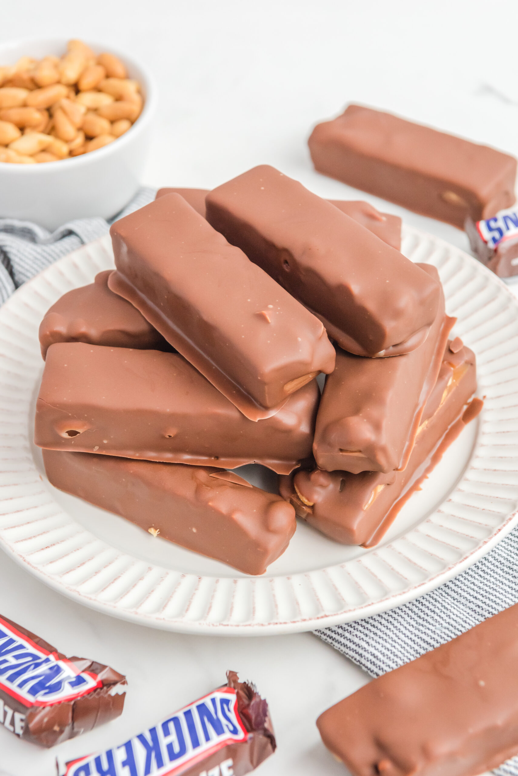 Homemade Snickers Candy Bars piled on a white serving plate 