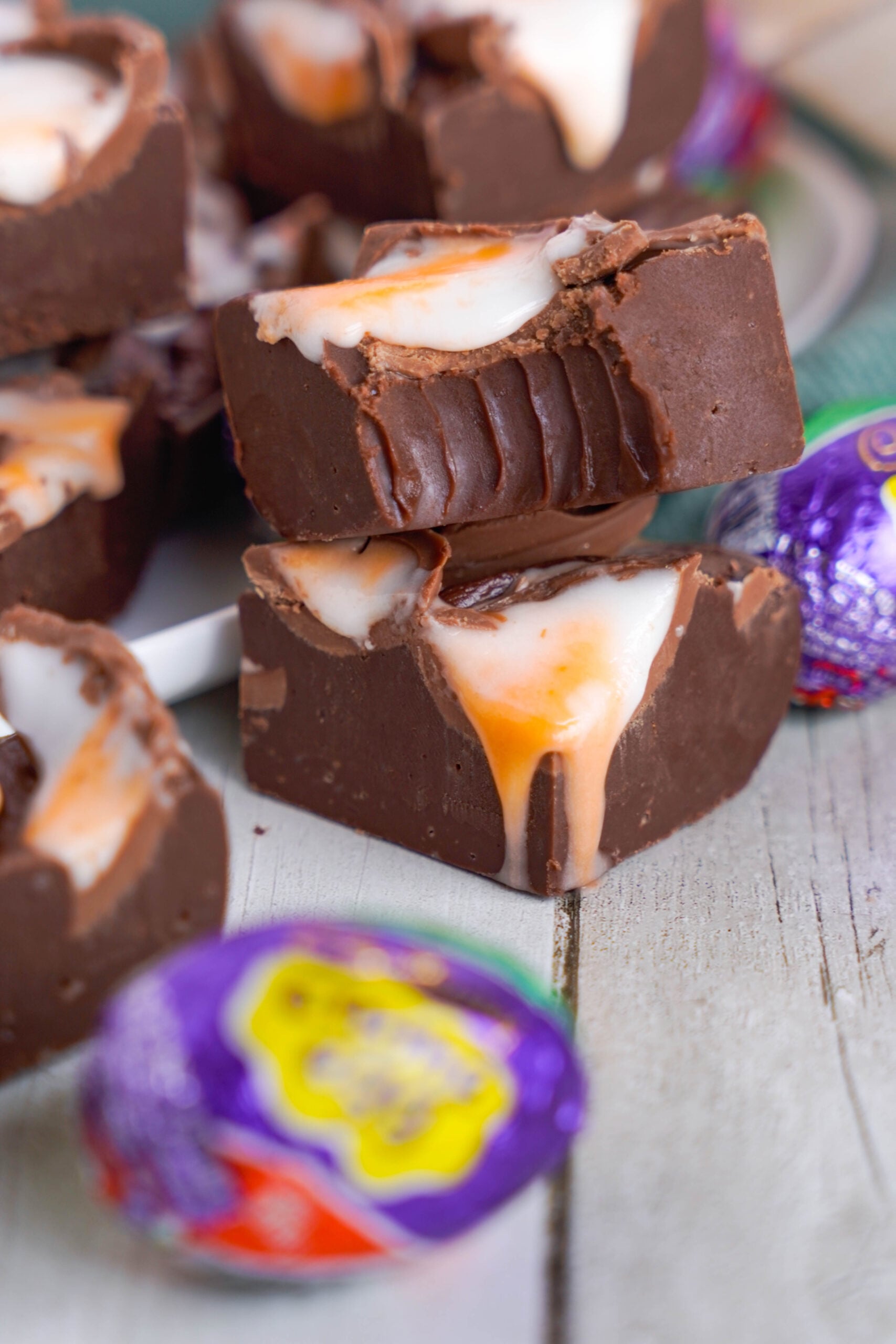 Front view of two pieces of Cadbury Cream Fudge stacked with a bite removed from the top piece.