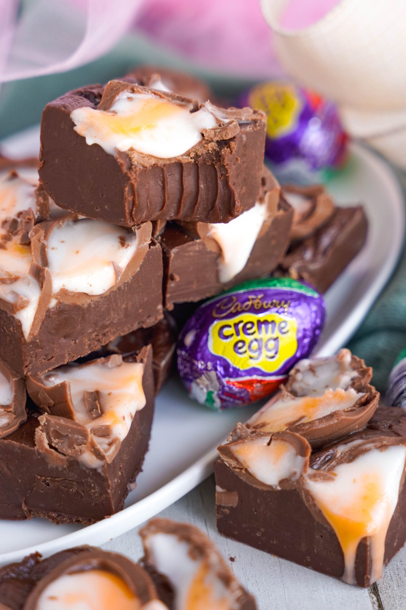 Front view of a stack of Cadbury Cream Fudge with a bite removed from the top piece.