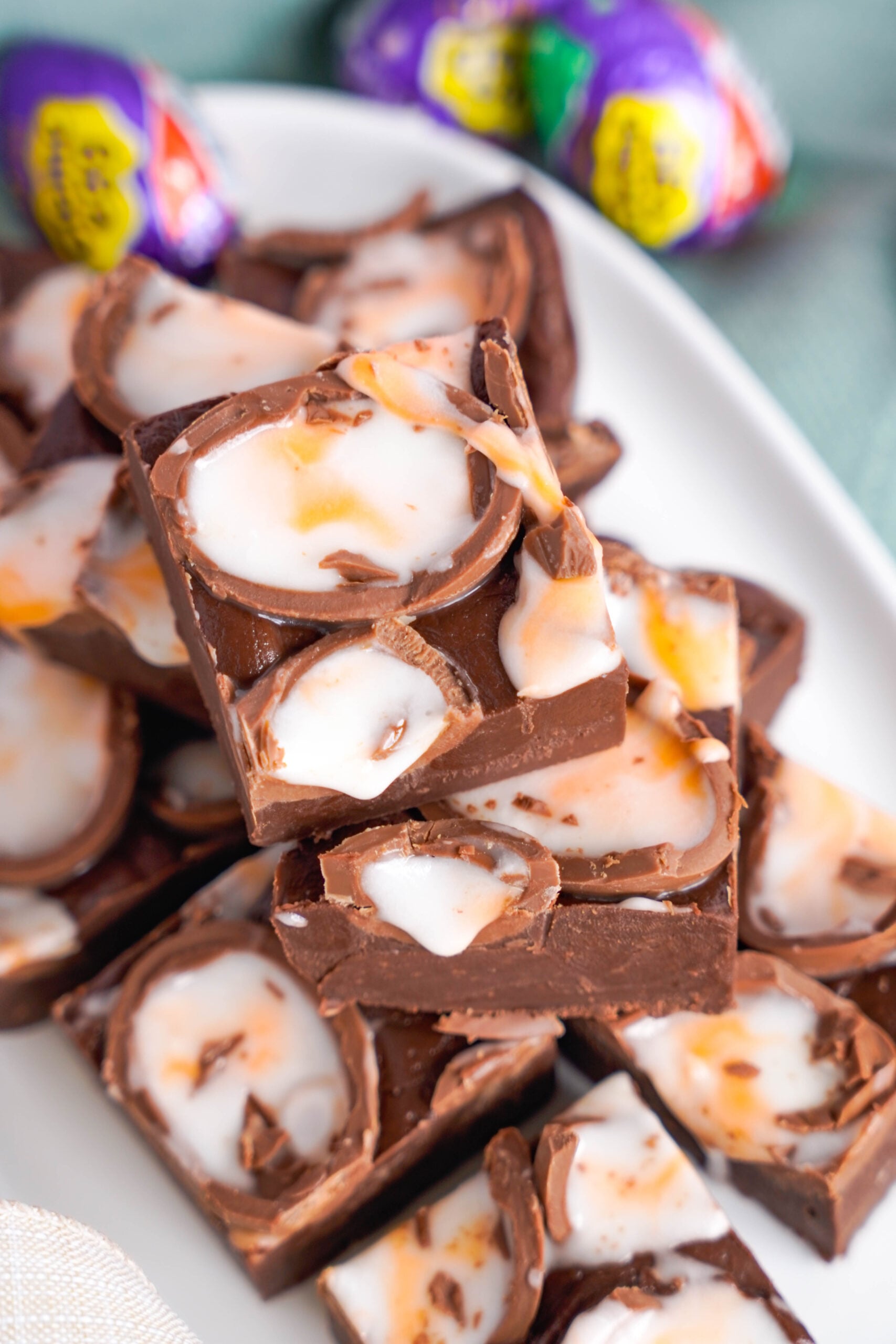 Overhead view of Cadbury Cream Fudge stacked on a white dish.