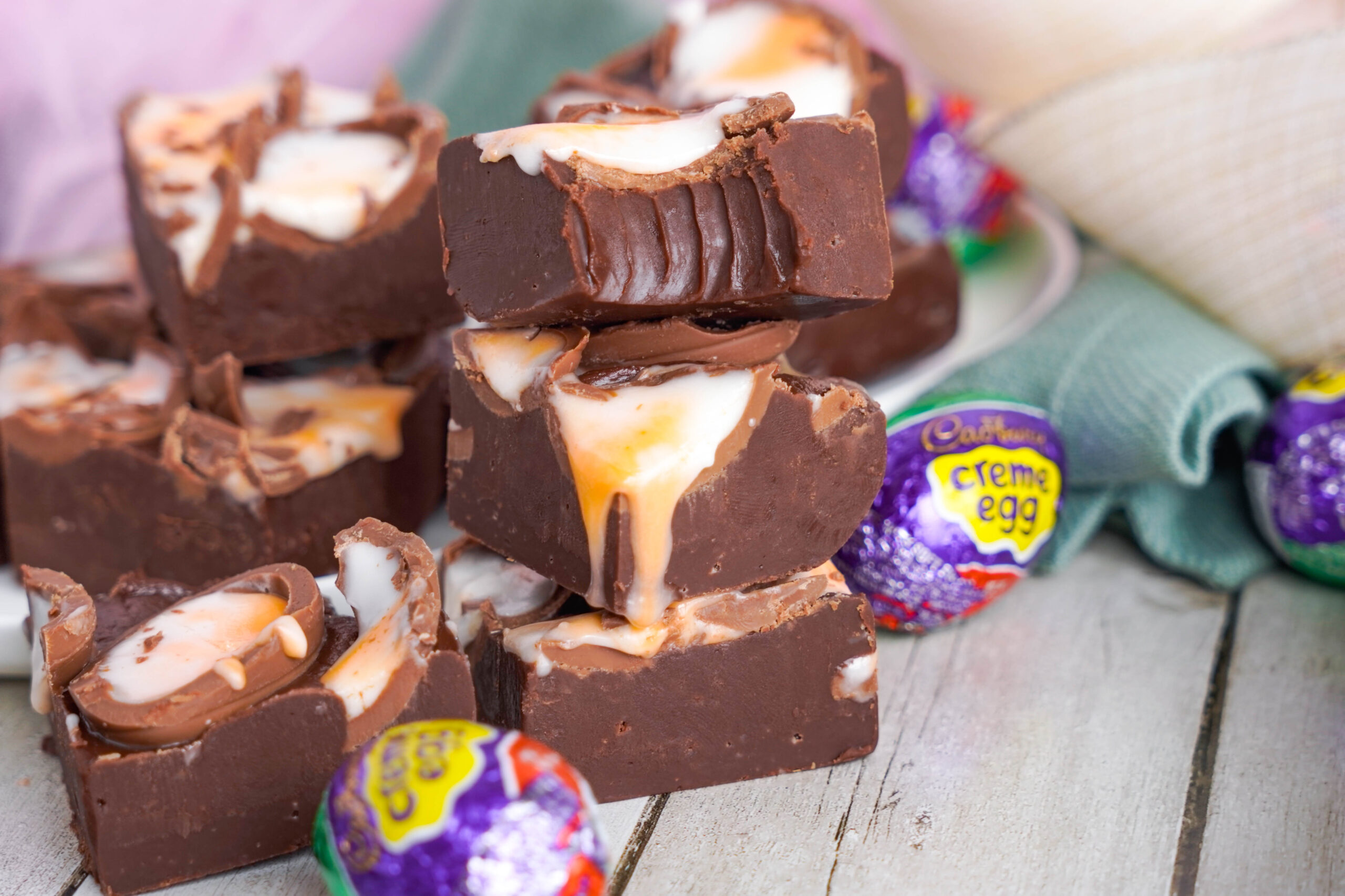 Front view of two pieces of Cadbury Cream Fudge stacked with a bite removed from the top piece.
