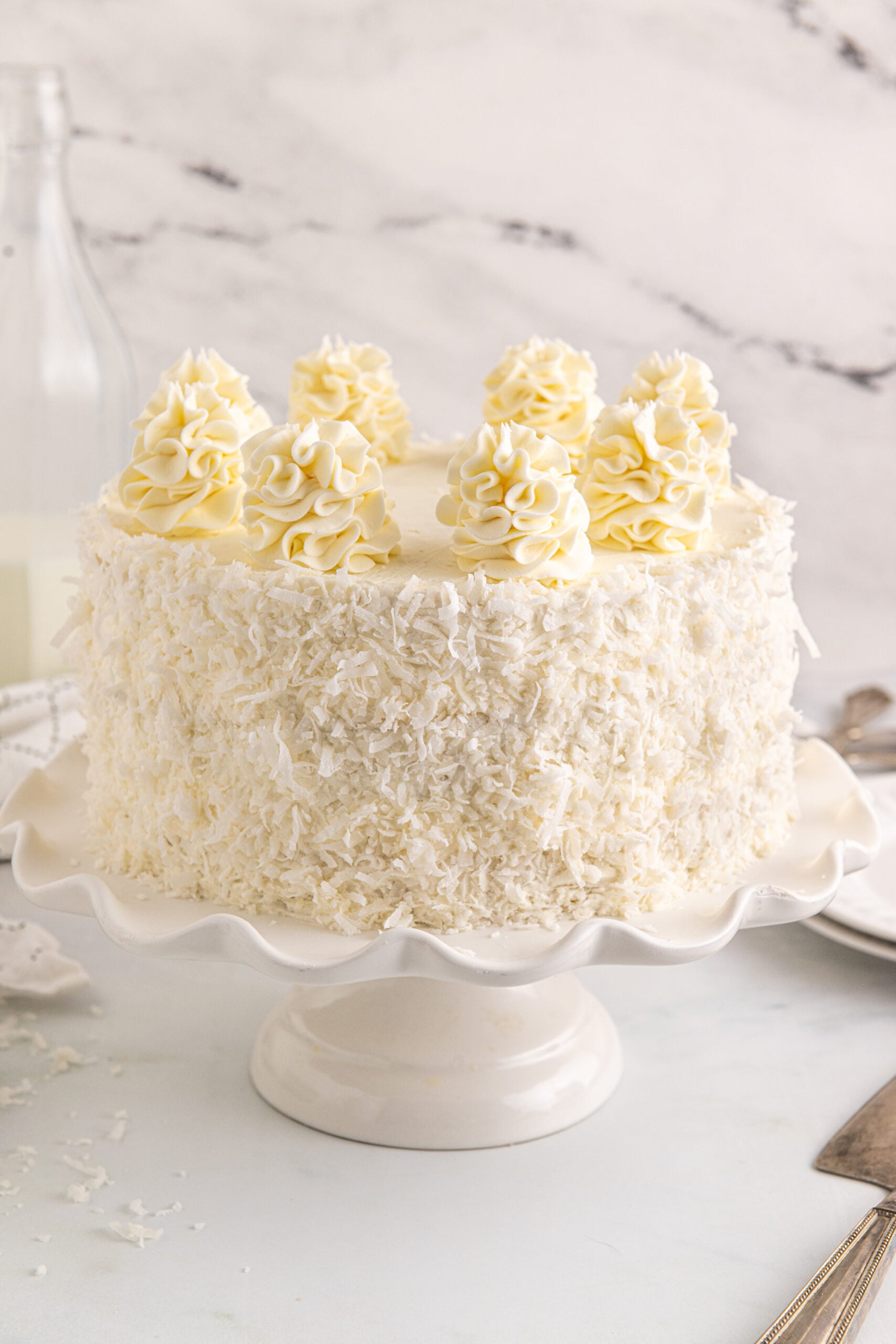 Front view of Coconut Layer Cake on a white cake stand.