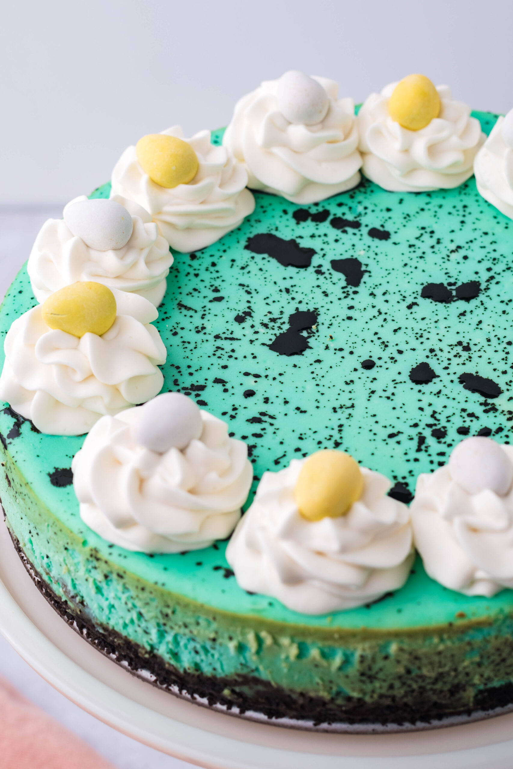 Close up view of Speckled Egg Cheesecake on a white cake stand.