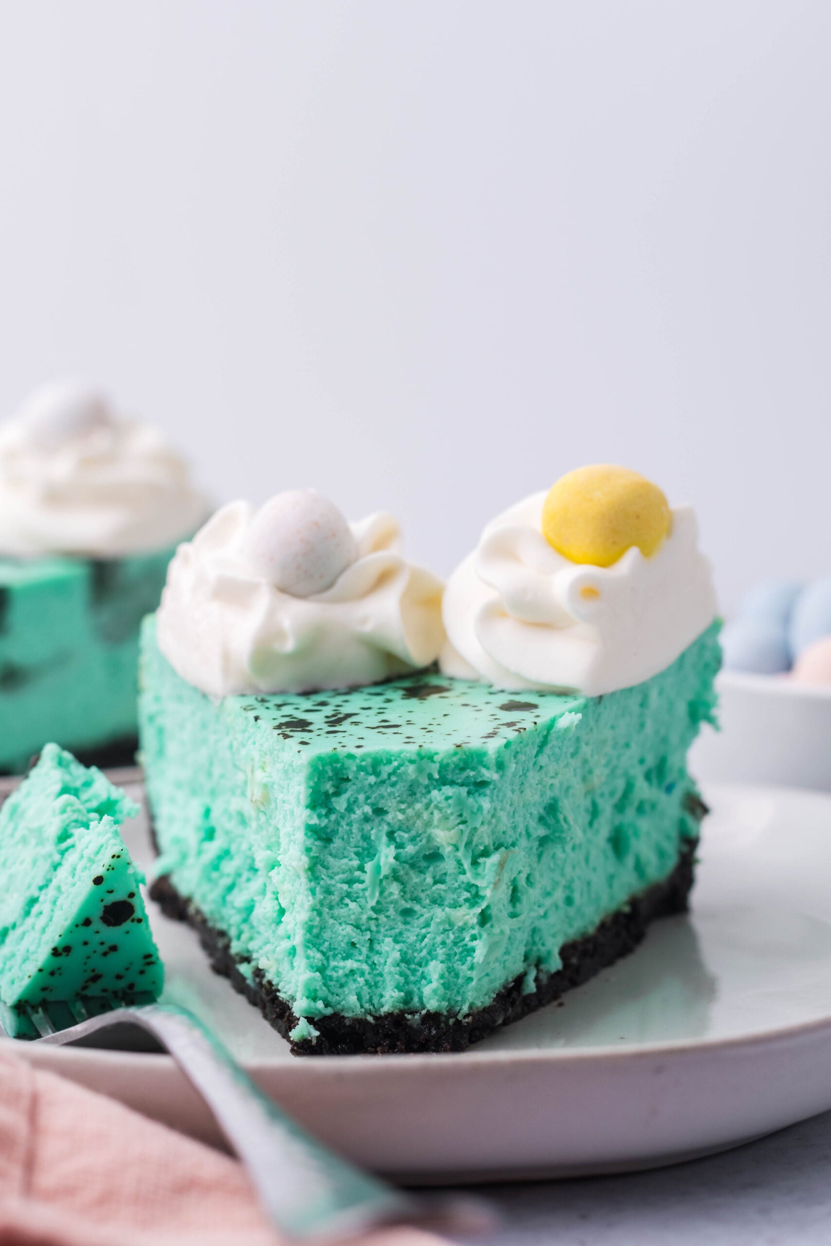 Front view of a slice of Speckled Egg Cheesecake with a bite removed by a silver fork.