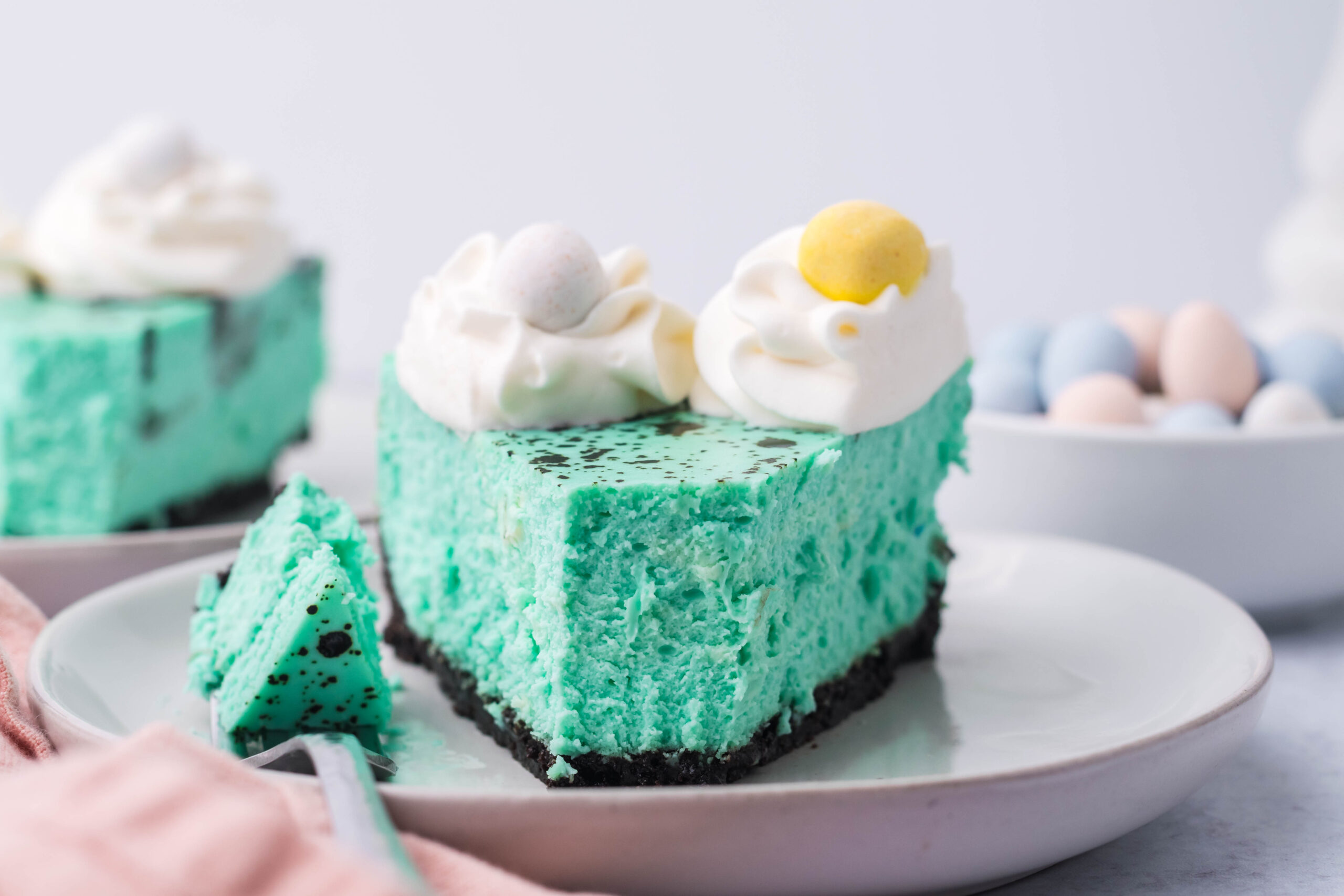 Front view of a slice of Speckled Egg Cheesecake with a bite removed by a silver fork.