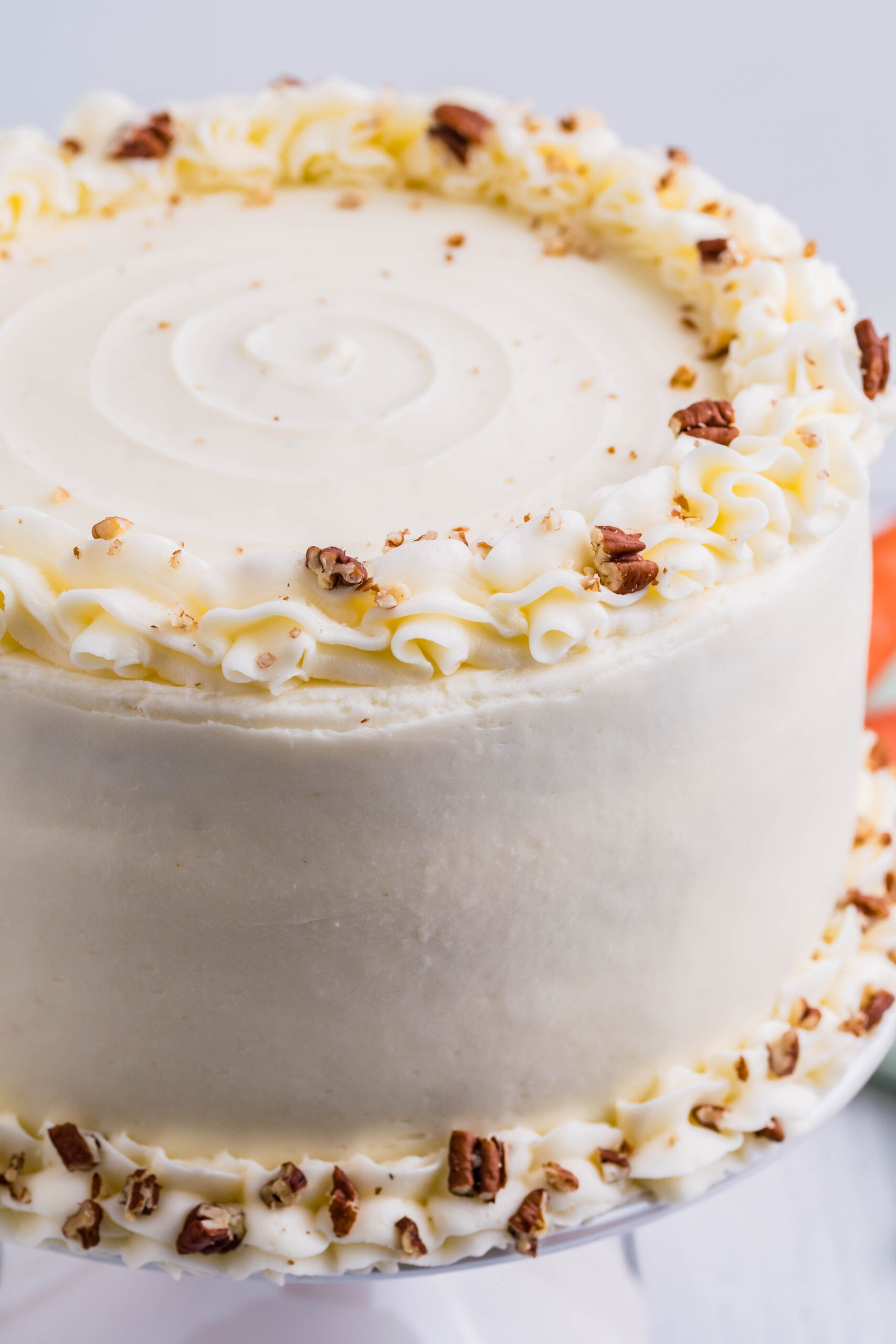 Close up view of Carrot Cake on a white cake stand.