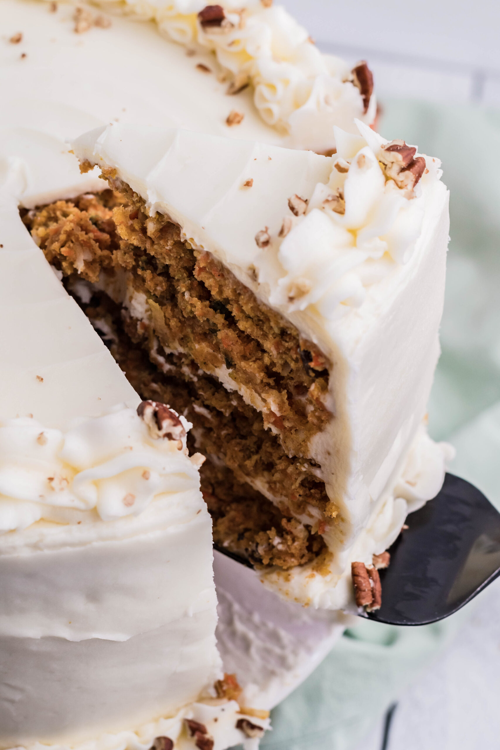 Close up view of a slice of Carrot Cake being removed by a black cake server.
