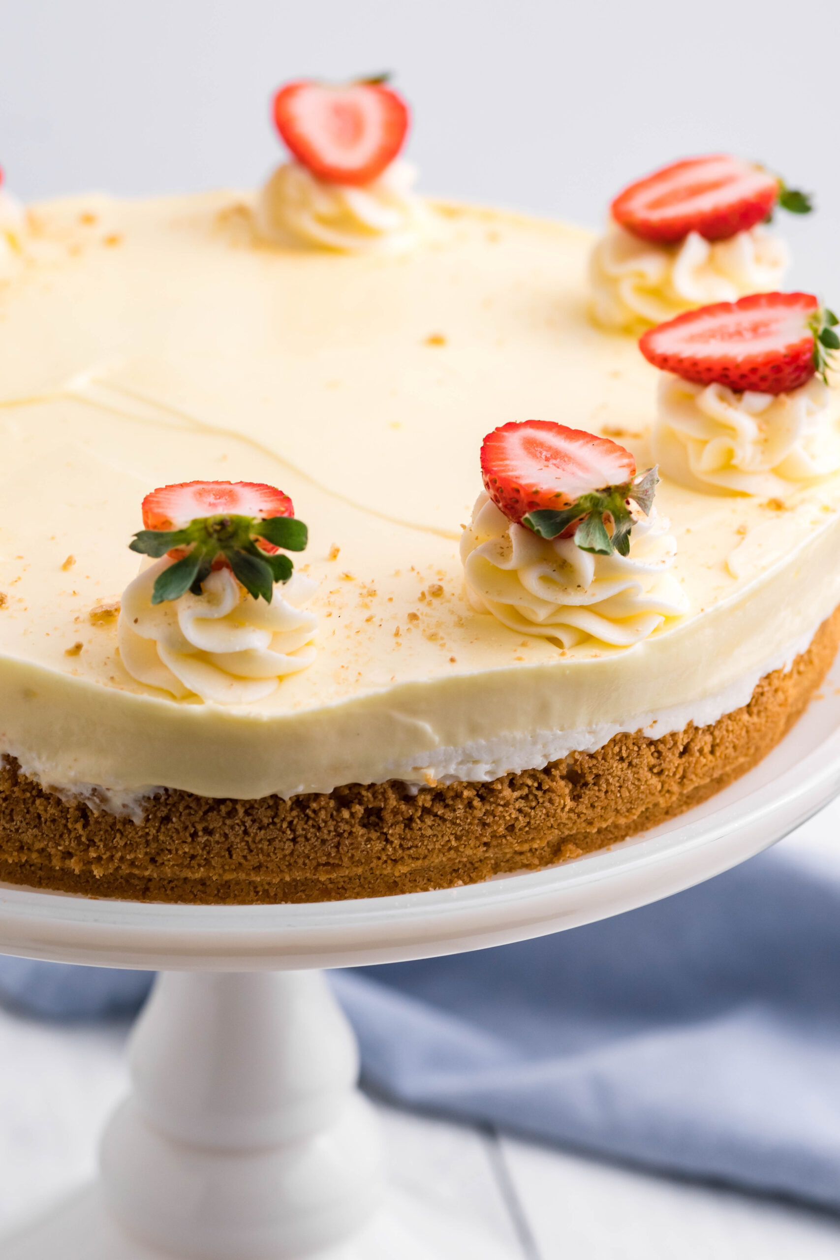 Close up view of Banana Cream Cheesecake on a white cake stand.