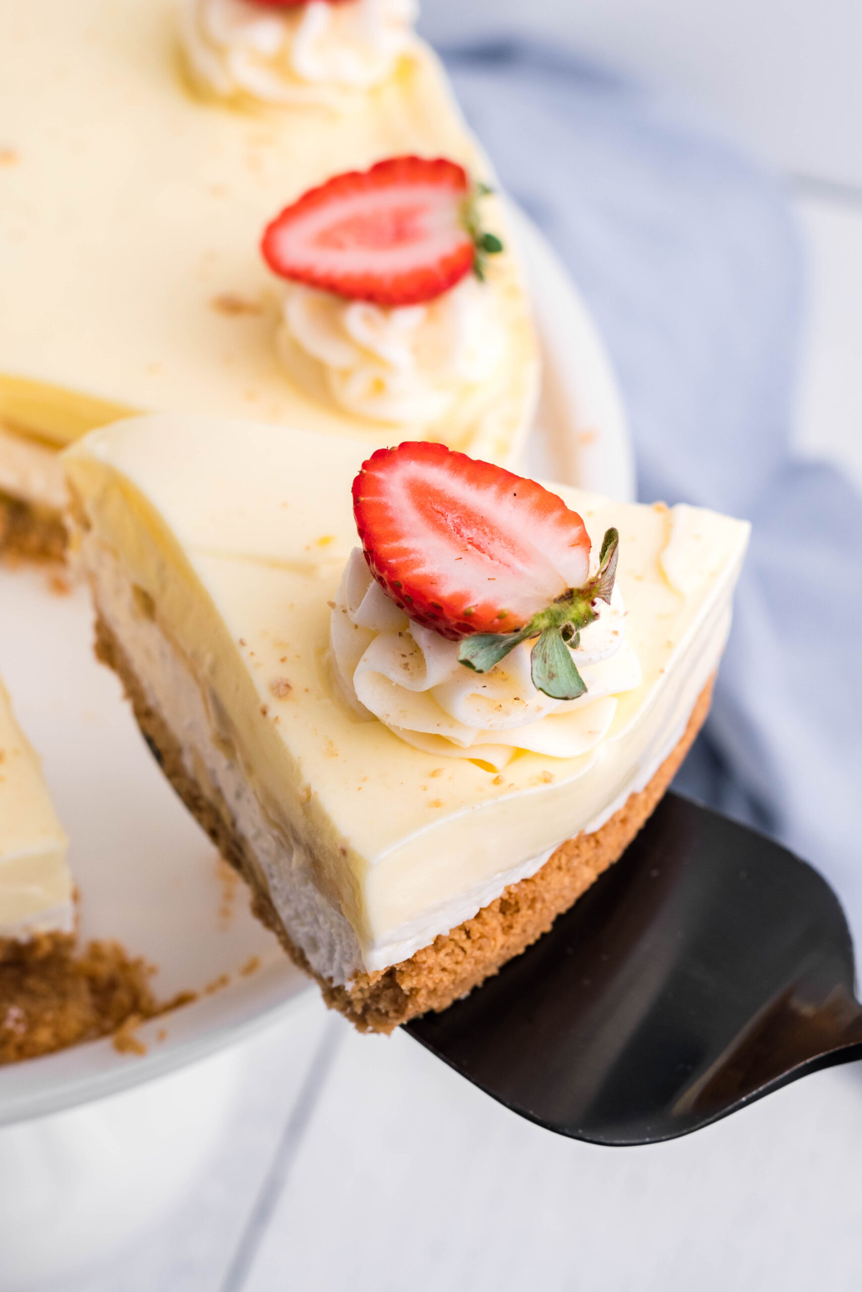 Close up view of a slice of Banana Cream Cheesecake on a black cake server.
