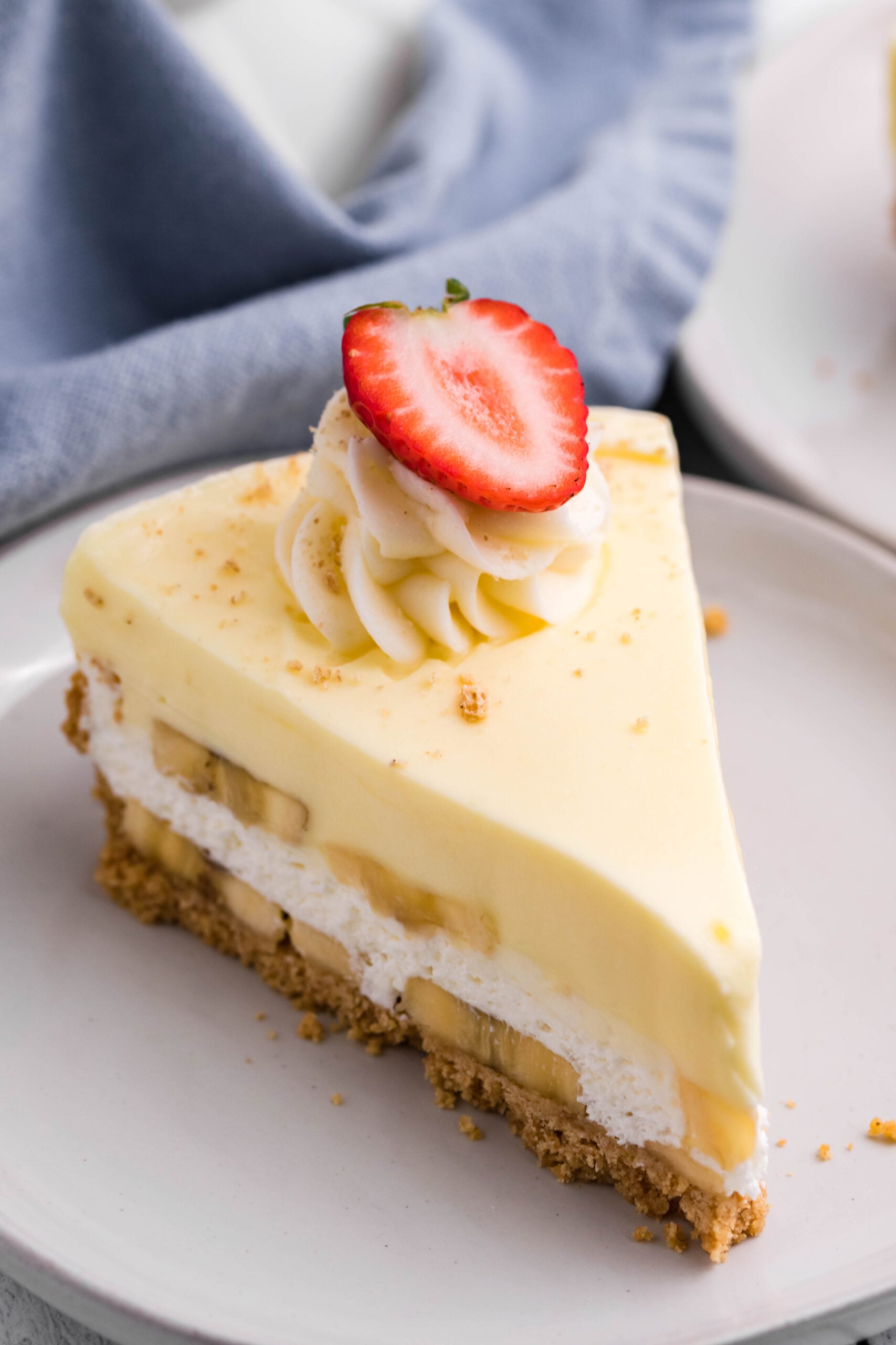 Front view of a slice of Banana Cream Cheesecake on a white plate.