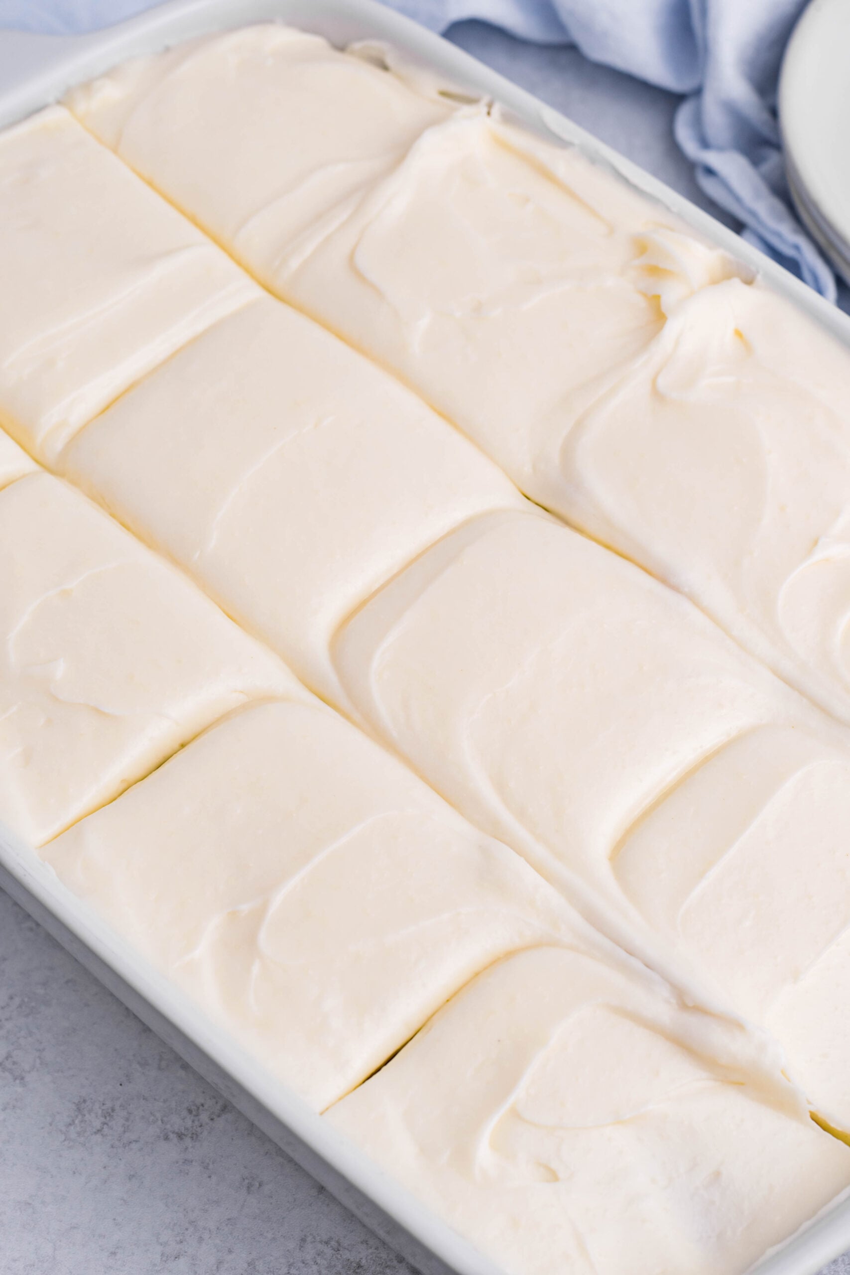 Close up view of Banana Sheet Cake in a white baking dish cut into slices.