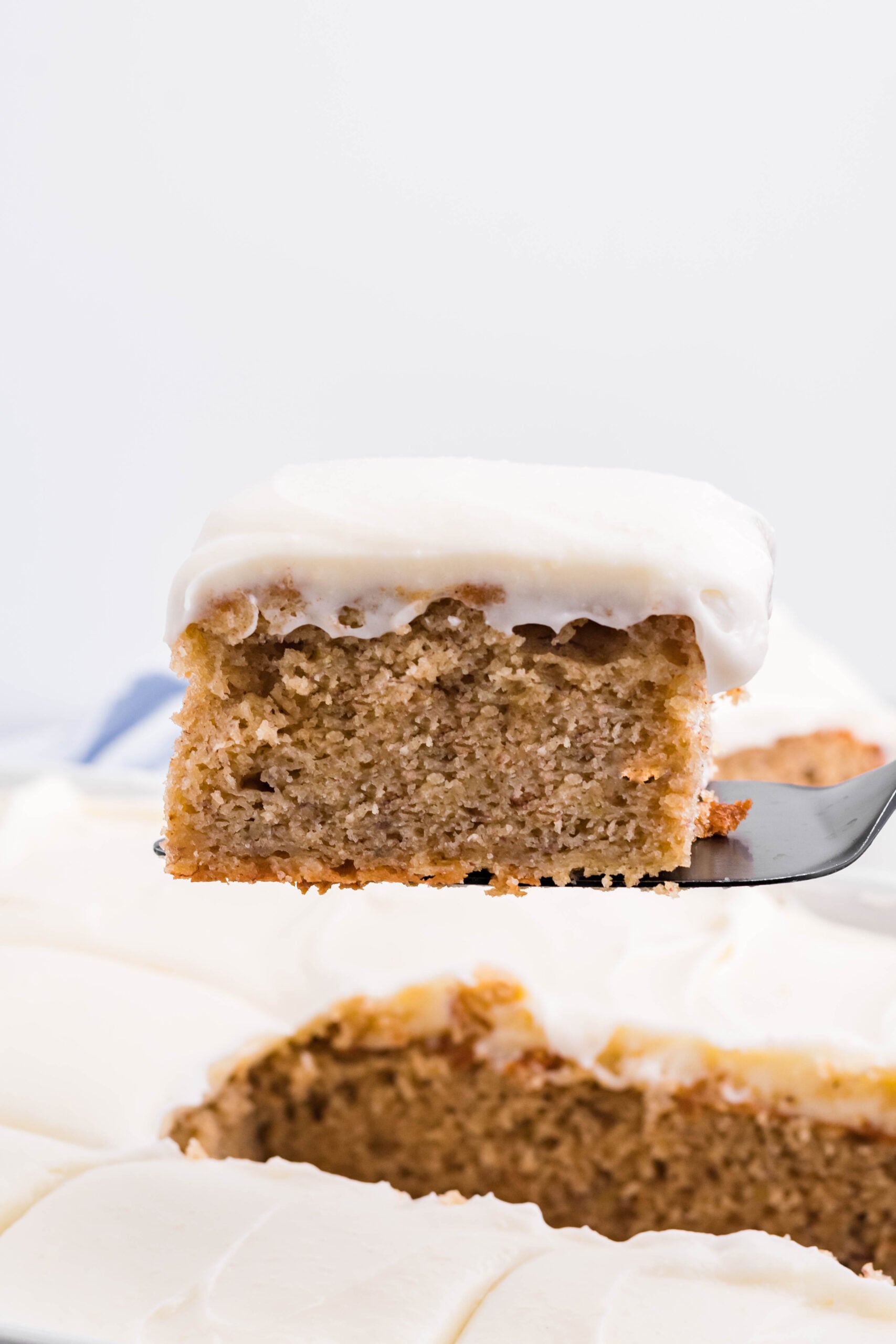 Side view of a slice of Banana Sheet Cake on a black cake server.