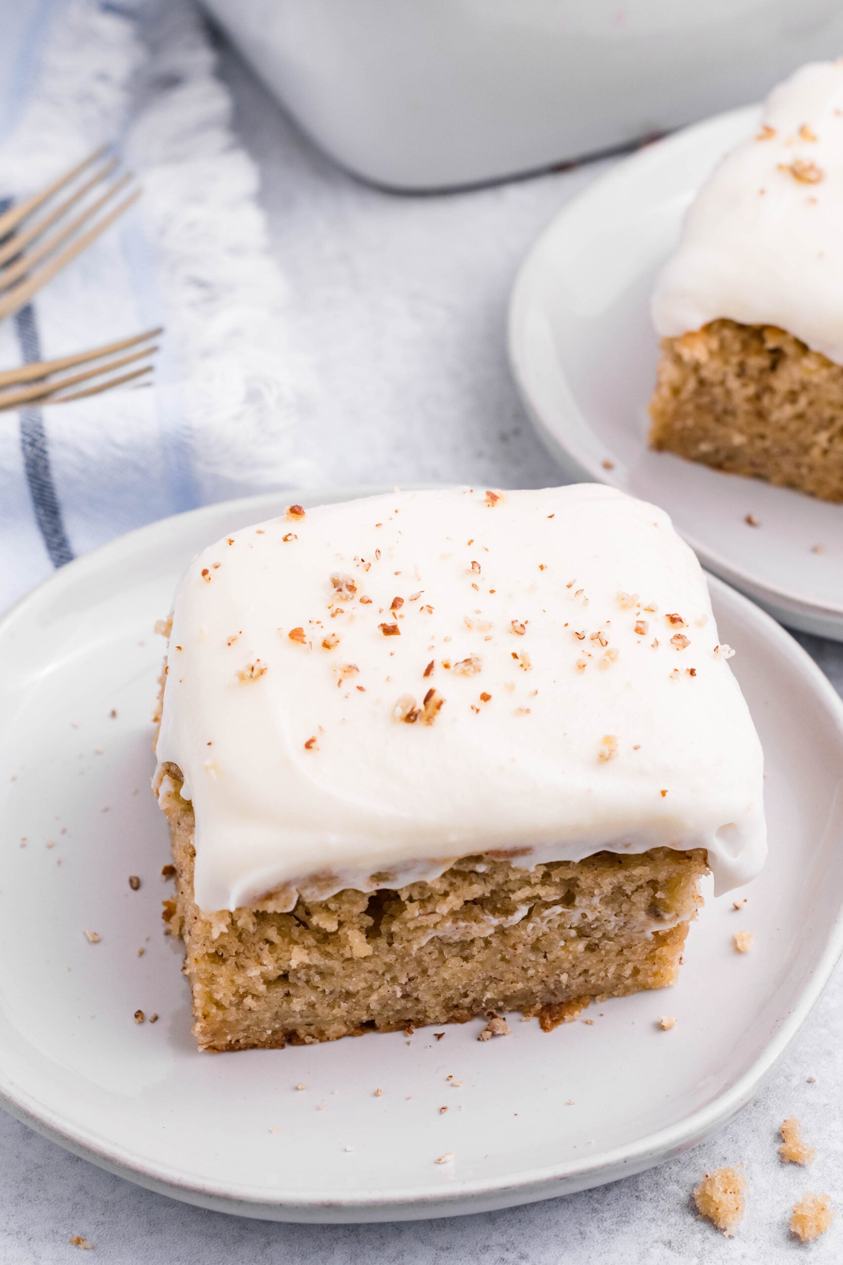 Close up view of a slice of Banana Sheet Cake on a white plate.