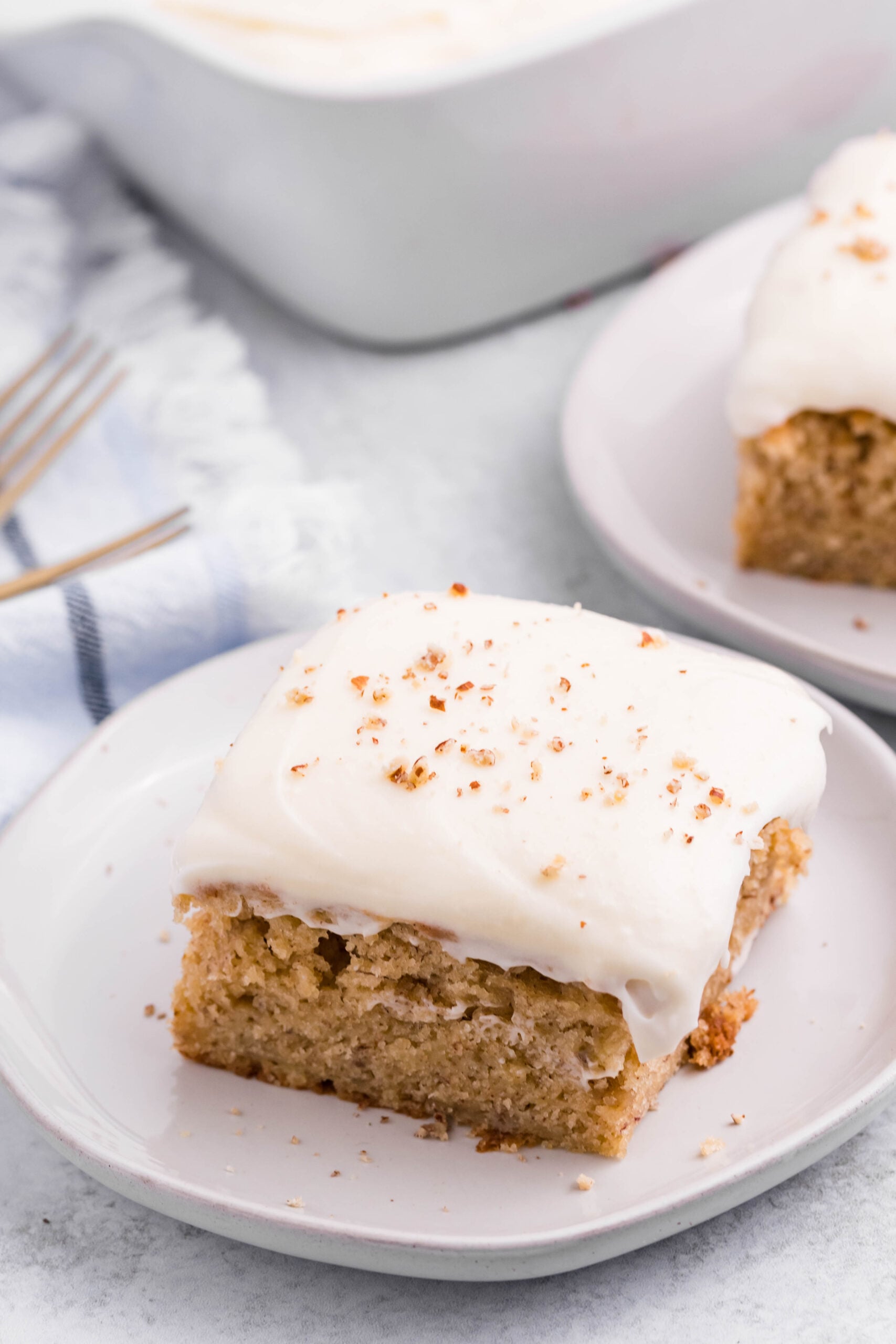 Close up view of a slice of Banana Sheet Cake on a white plate.