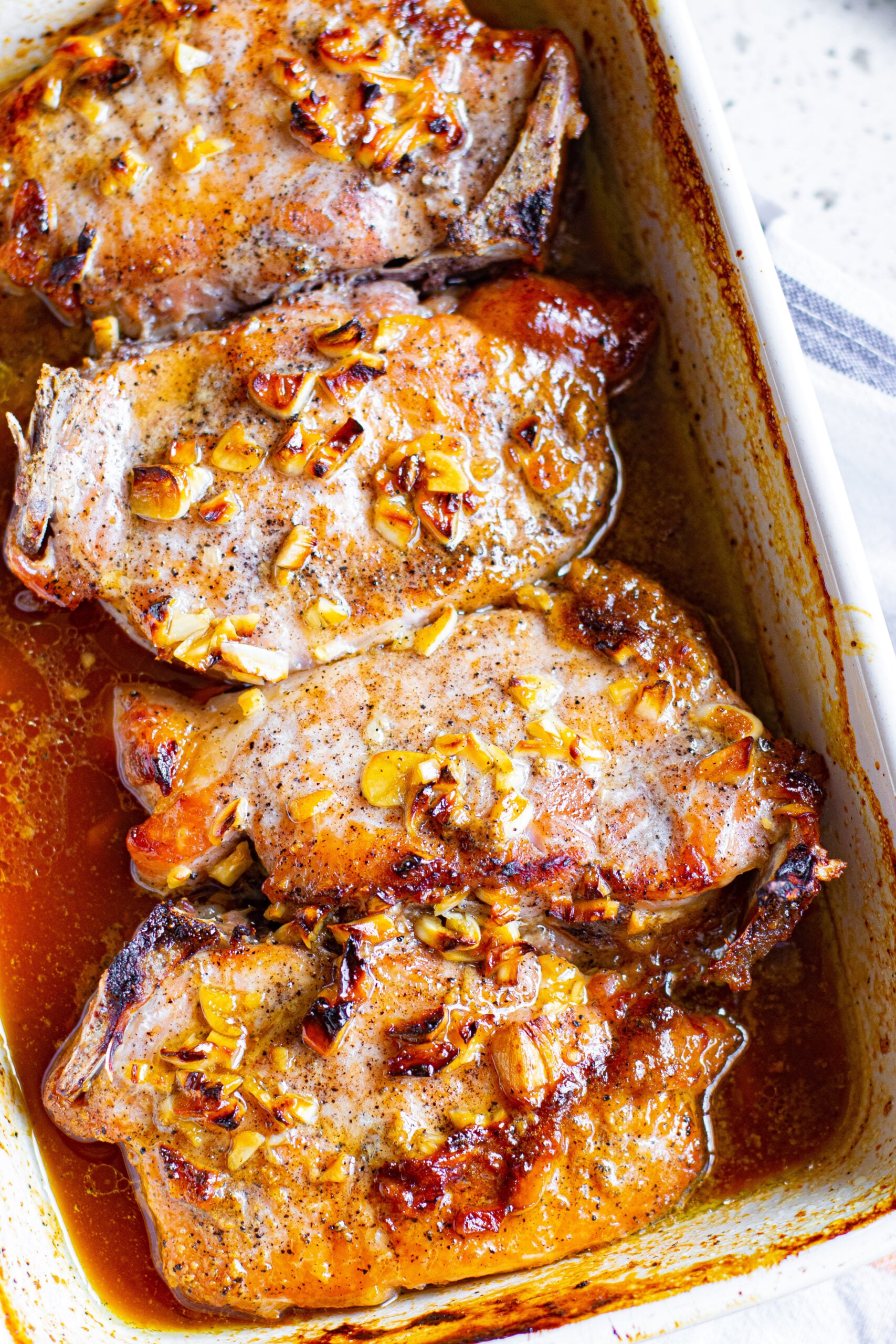 Close up view of Honey Garlic Pork Chops in a white baking dish.
