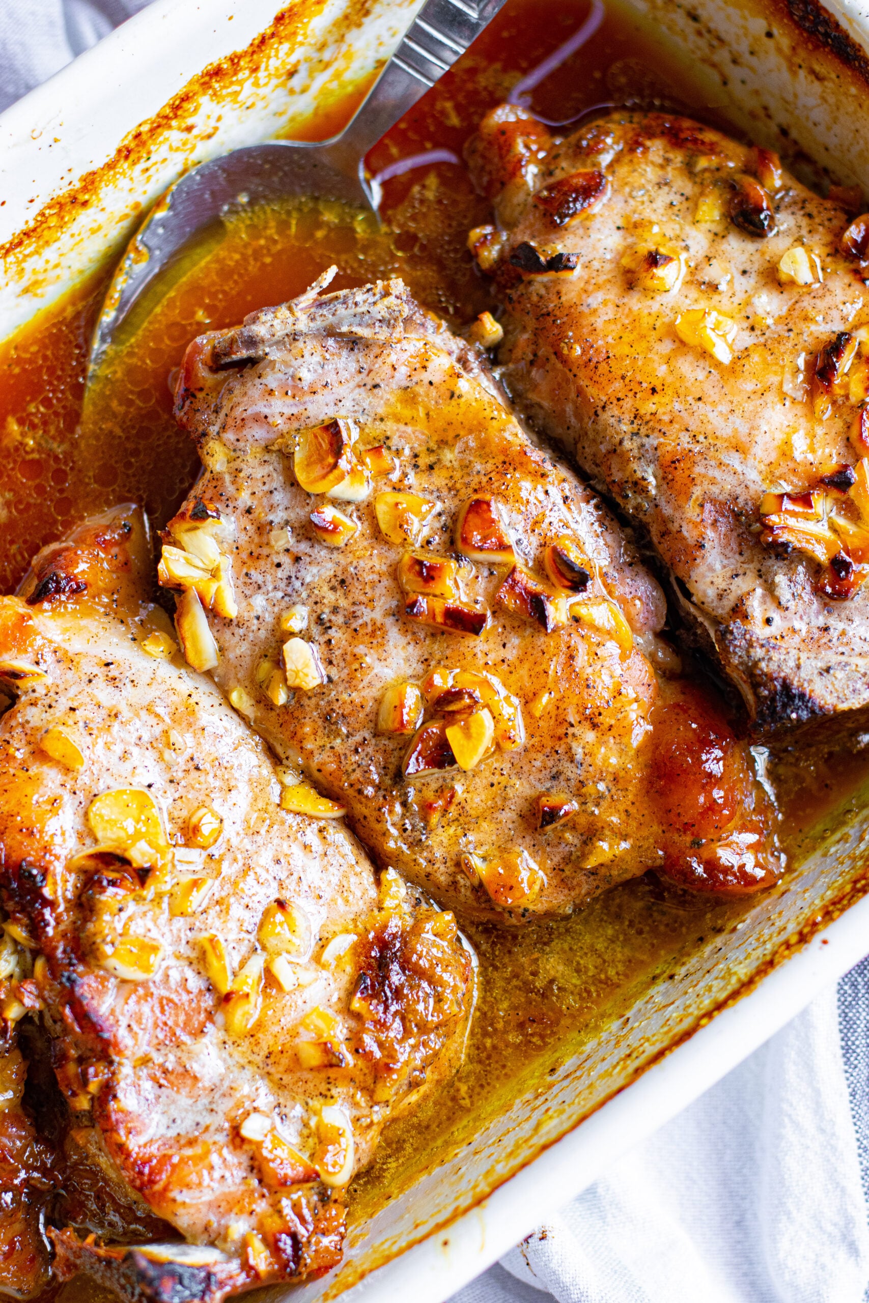 Close up view of Honey Garlic Pork Chops in a white baking dish.