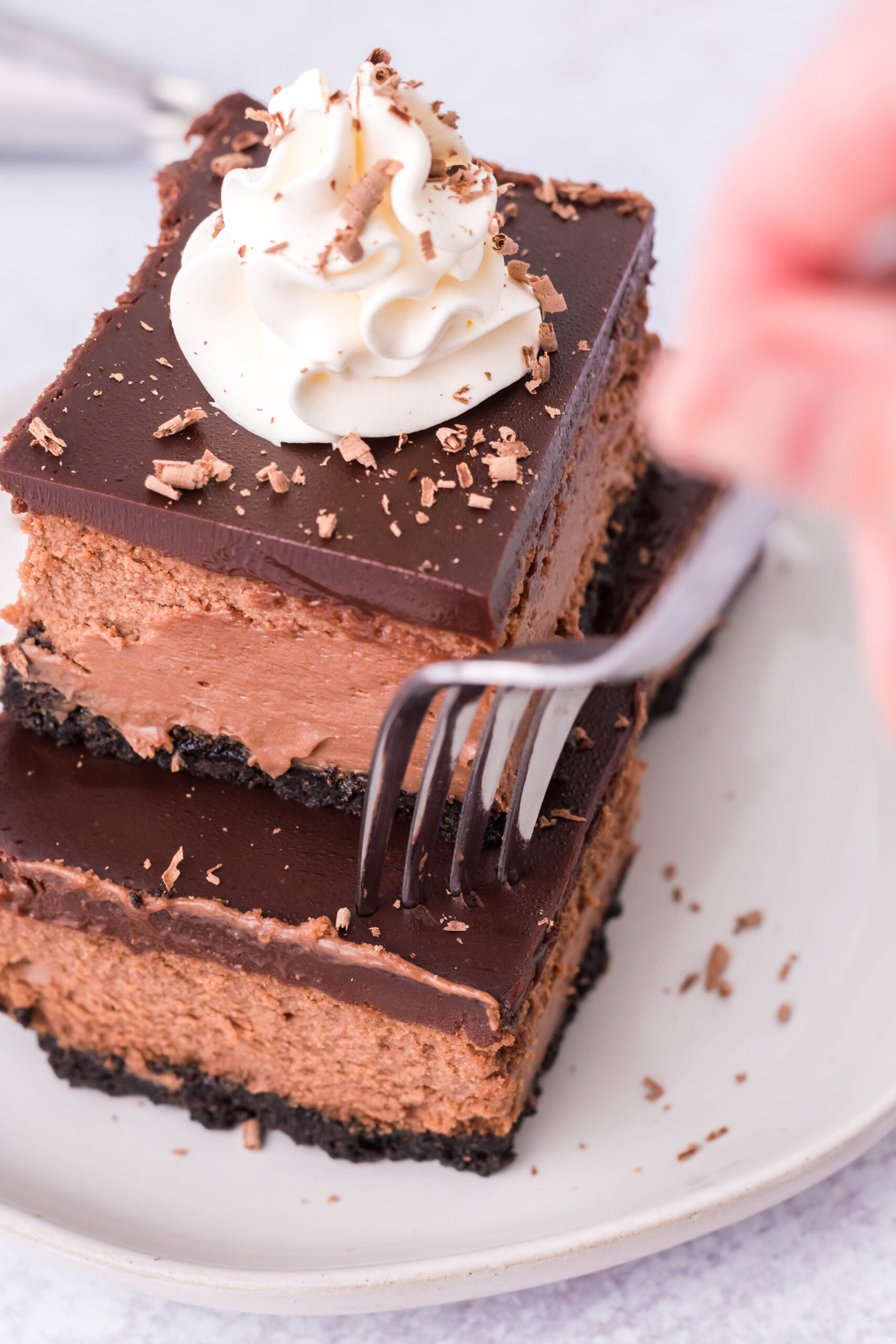 A fork removing a bite of chocolate cheesecake from one of the bars. 