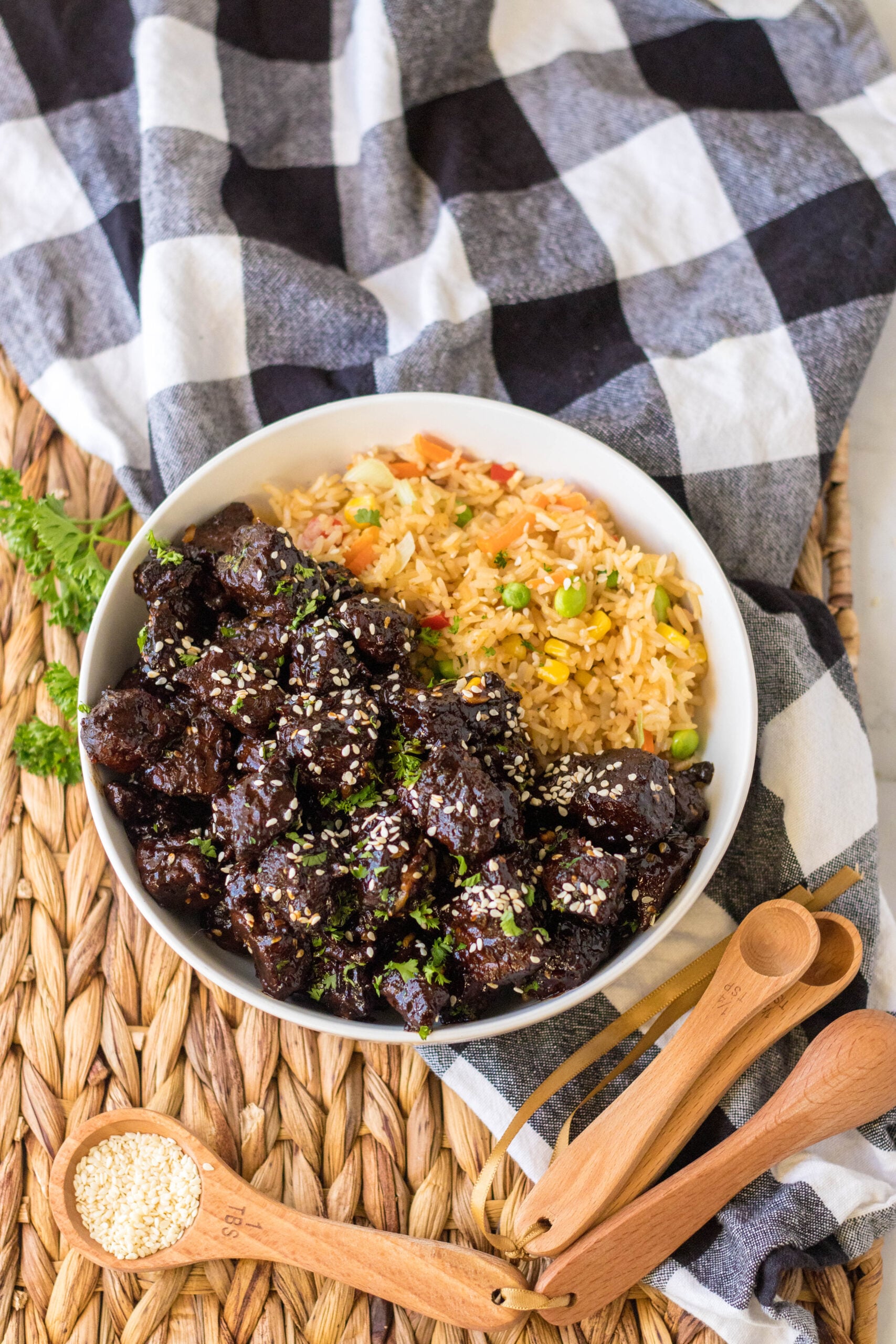 Overhead view of Slow Cooker Honey Garlic Steak Bites in a white bowl served with fried rice.