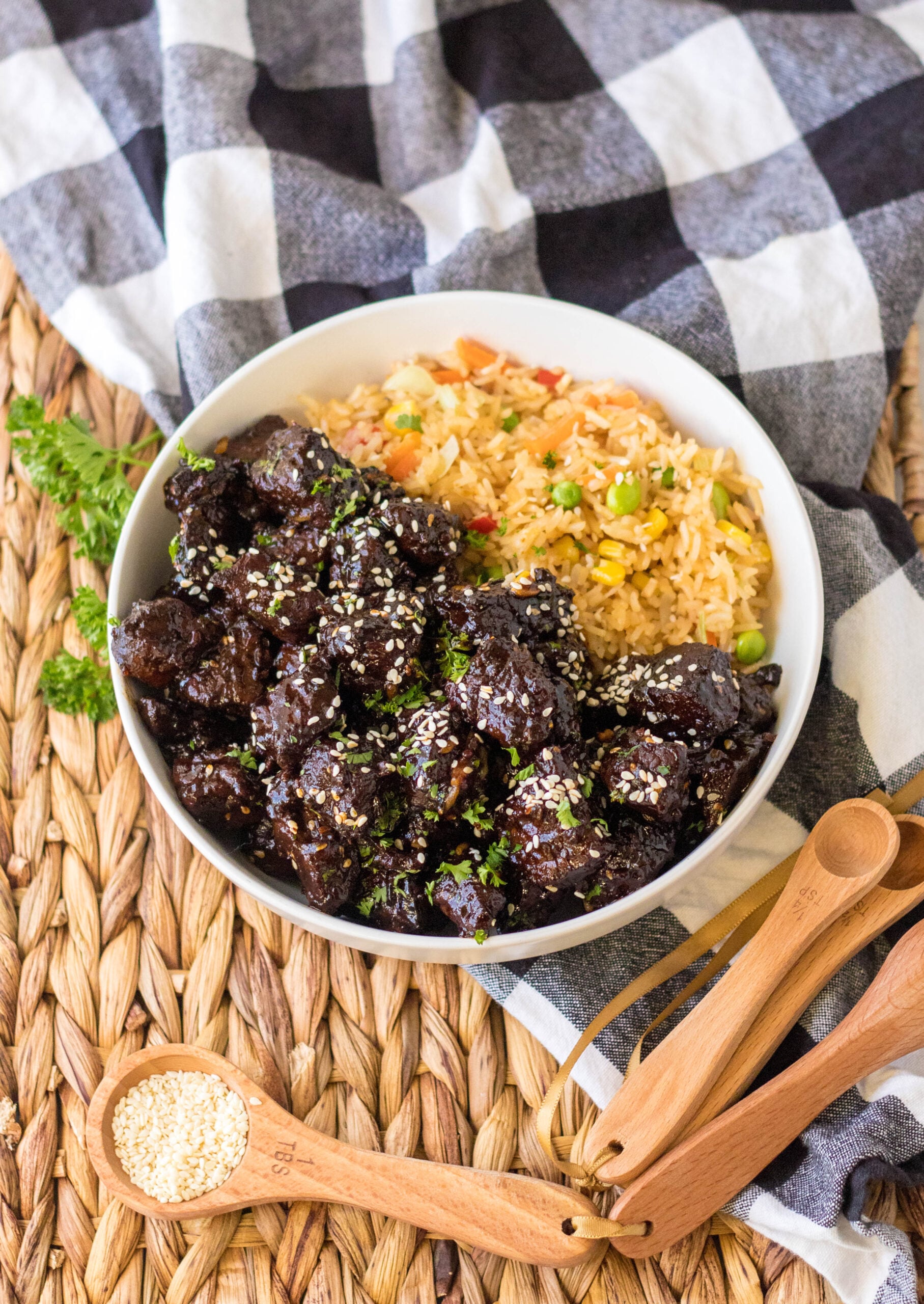 Overhead view of Slow Cooker Honey Garlic Steak Bites in a white bowl served with fried rice.