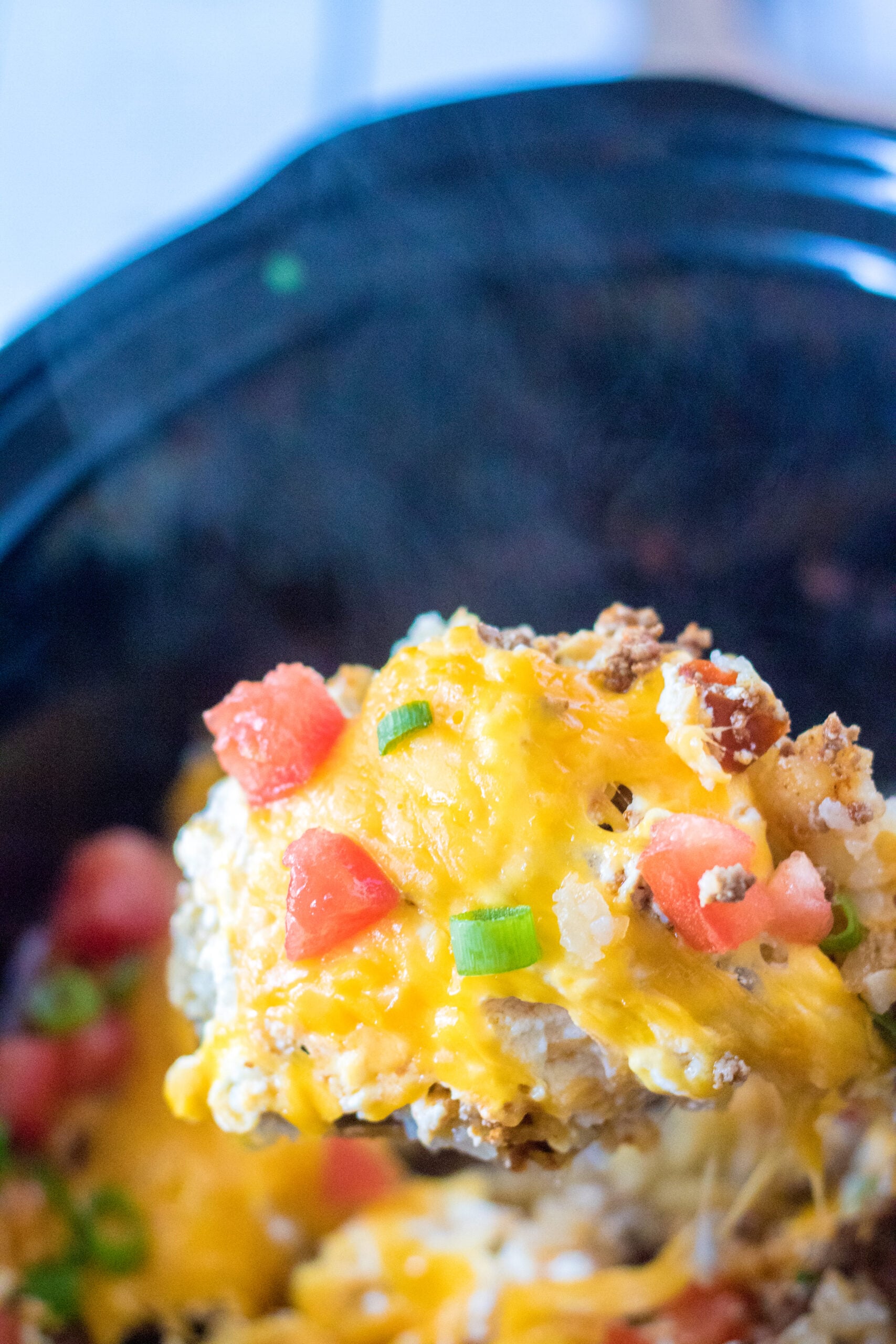 Close up view of a wooden spoon removing a serving of Slow Cooker John Wayne Casserole.