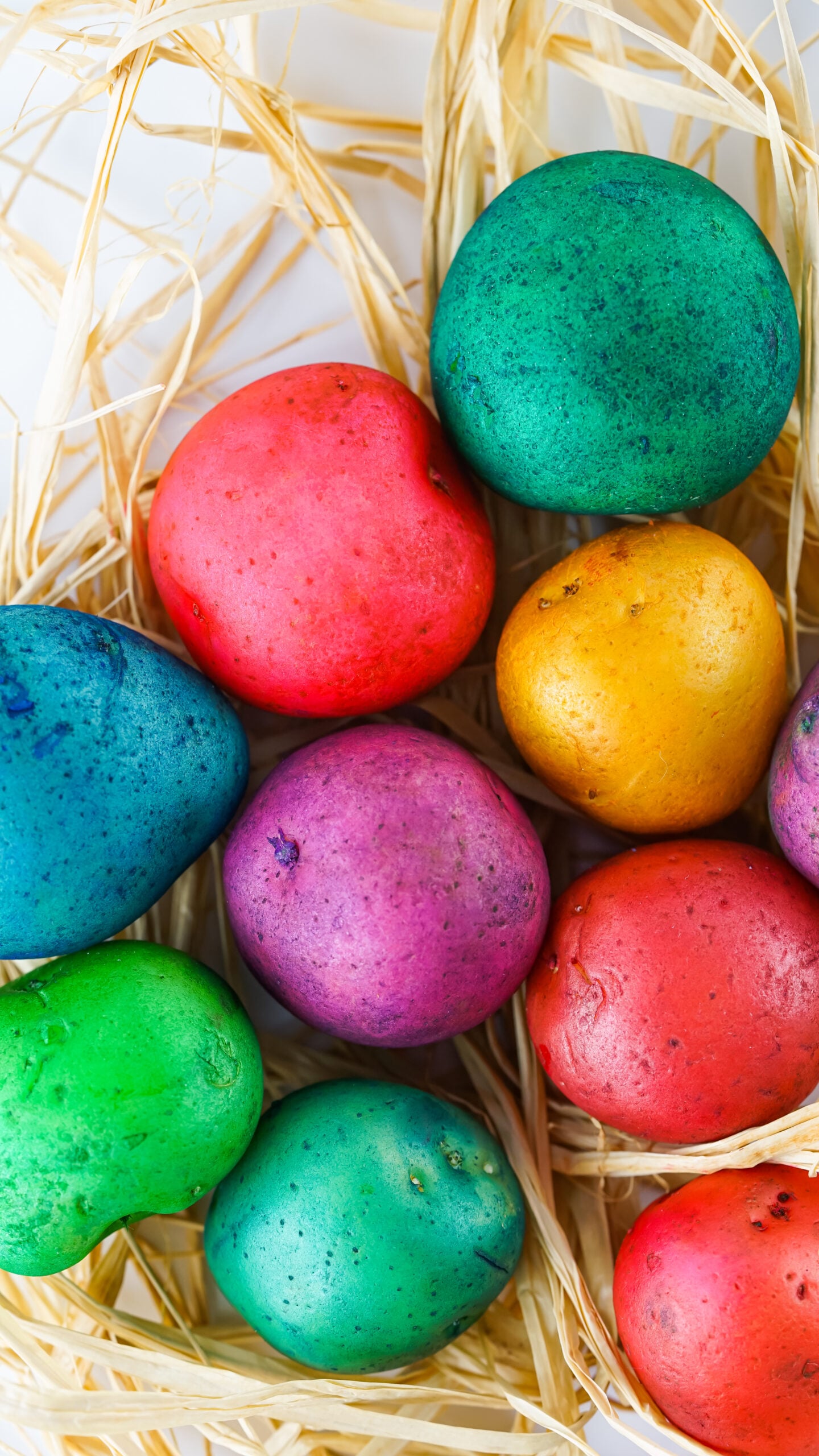 Overhead view of Dyed Easter Egg Potatoes on a bed of straw.
