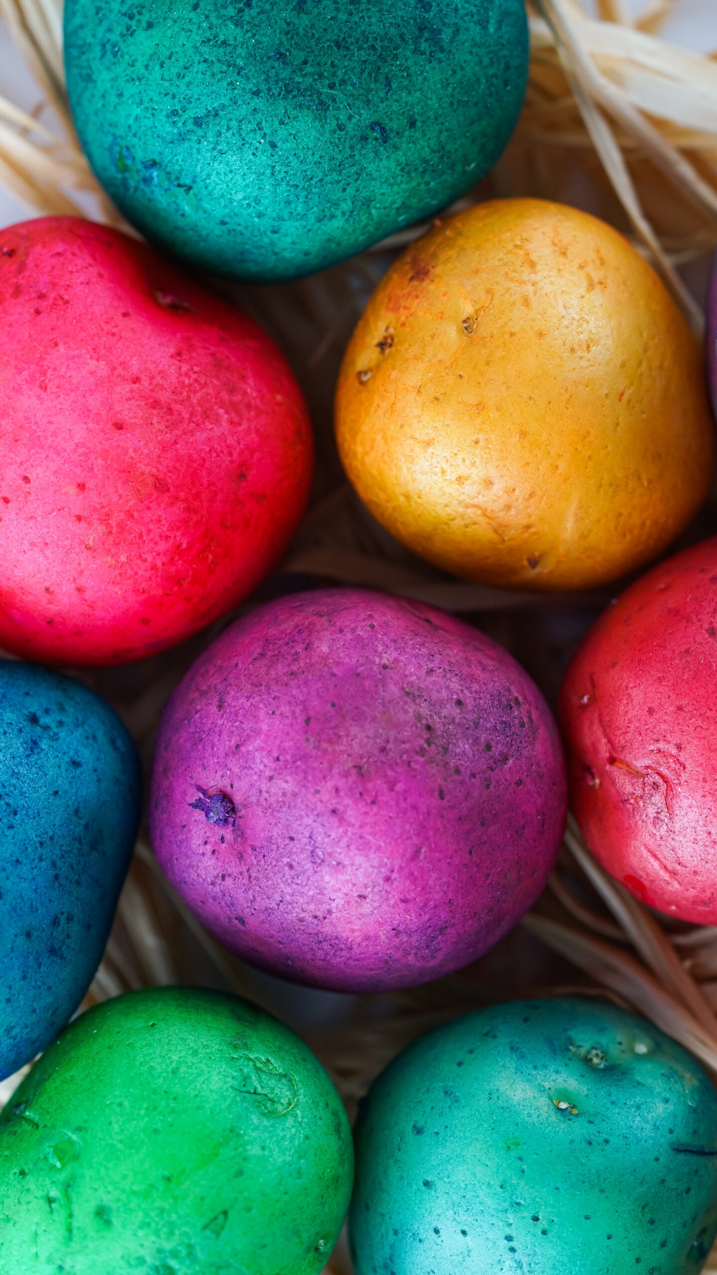 Overhead view of Dyed Easter Egg Potatoes on a bed of straw.