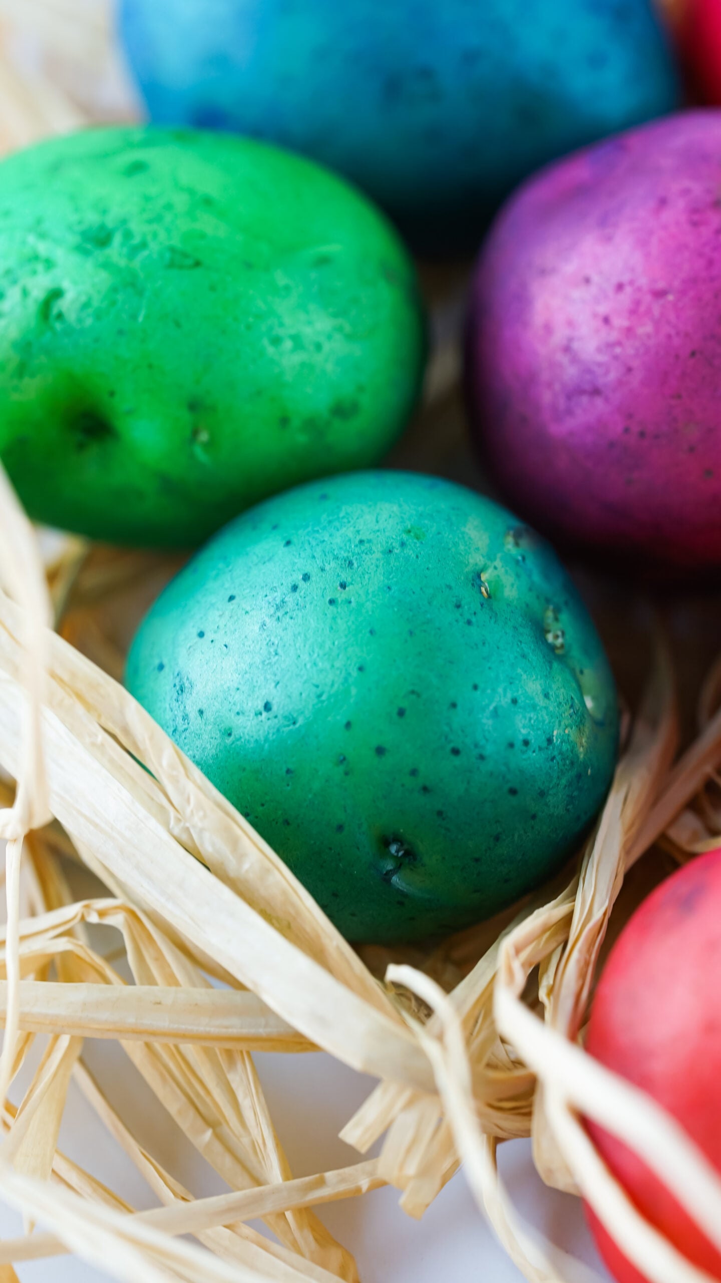 Close up view of Dyed Easter Egg Potatoes on a bed of straw.