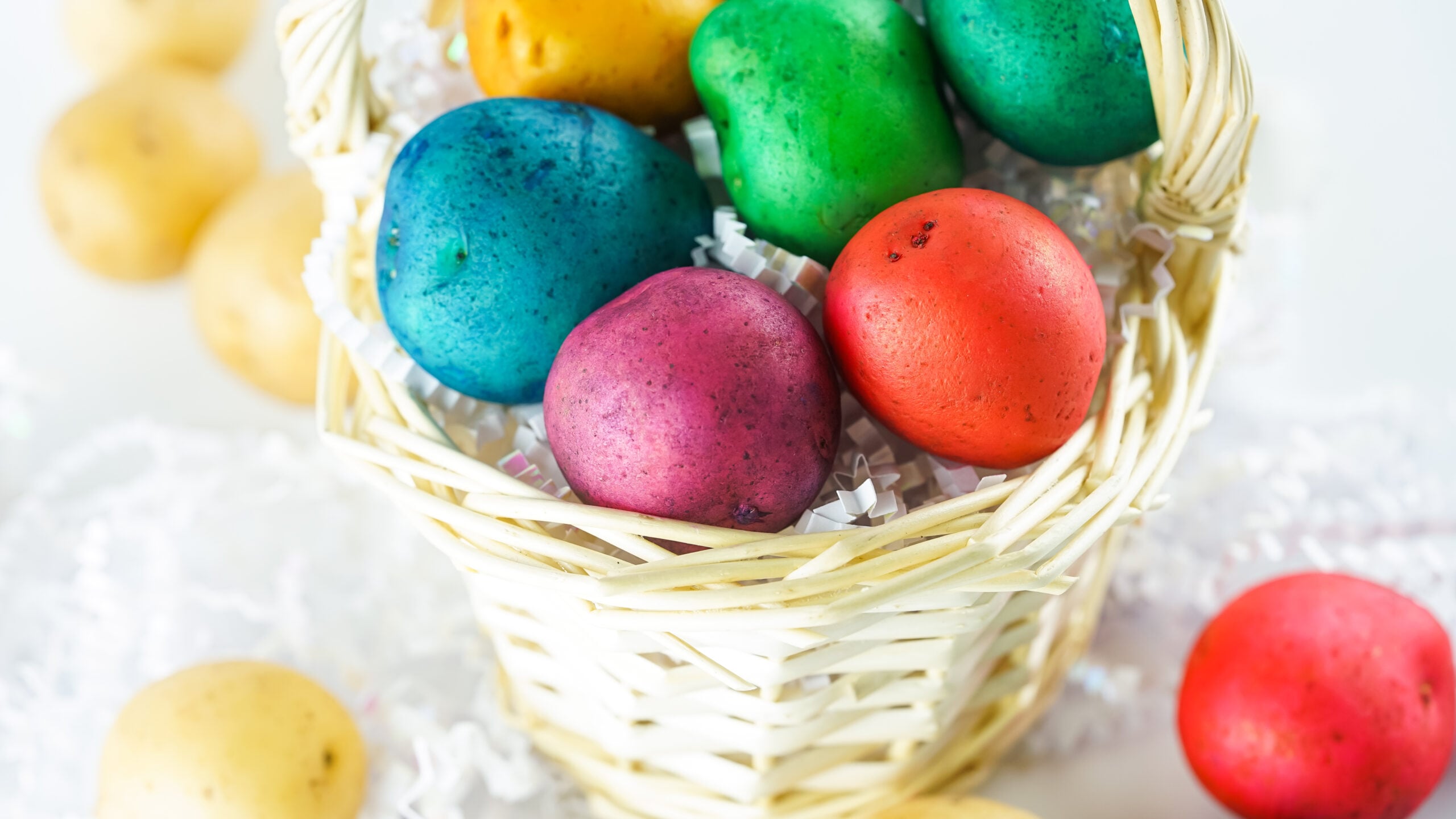 Front view of Dyed Easter Egg Potatoes in a tan basket.
