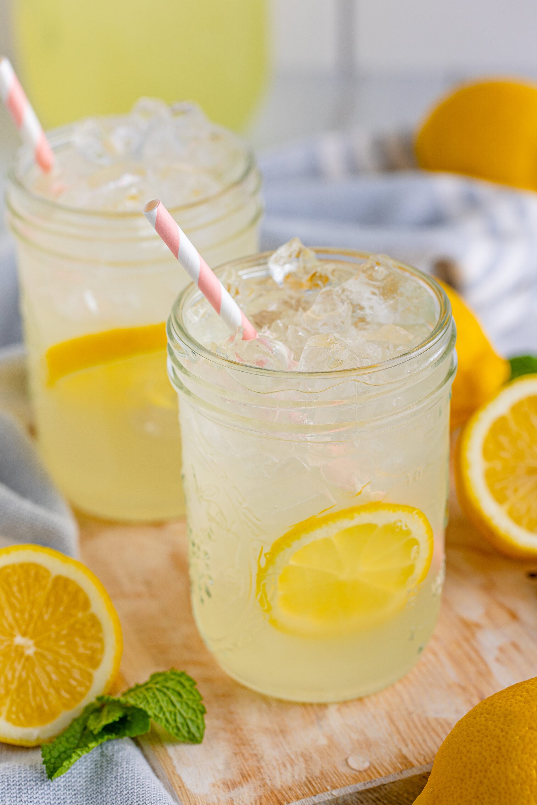 Front view of Homemade Lemonade in two mason jars garnished with lemon slices.