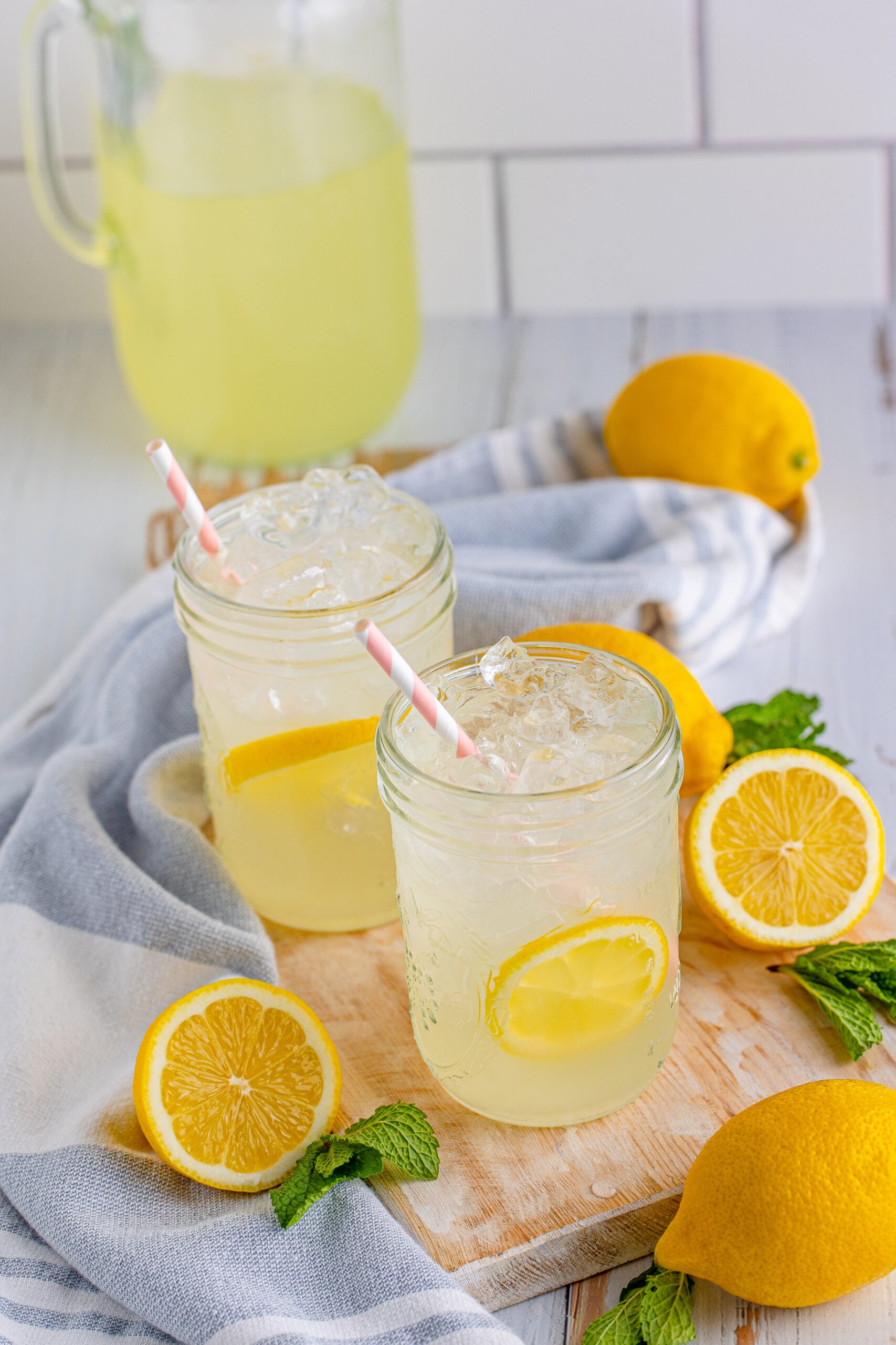 Front view of Homemade Lemonade in two mason jars garnished with lemon slices.