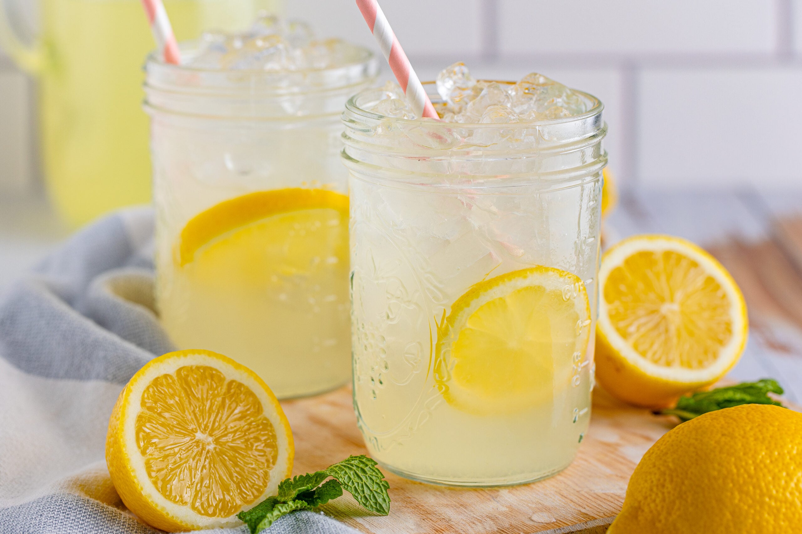 Front view of Homemade Lemonade in two mason jars garnished with lemon slices.