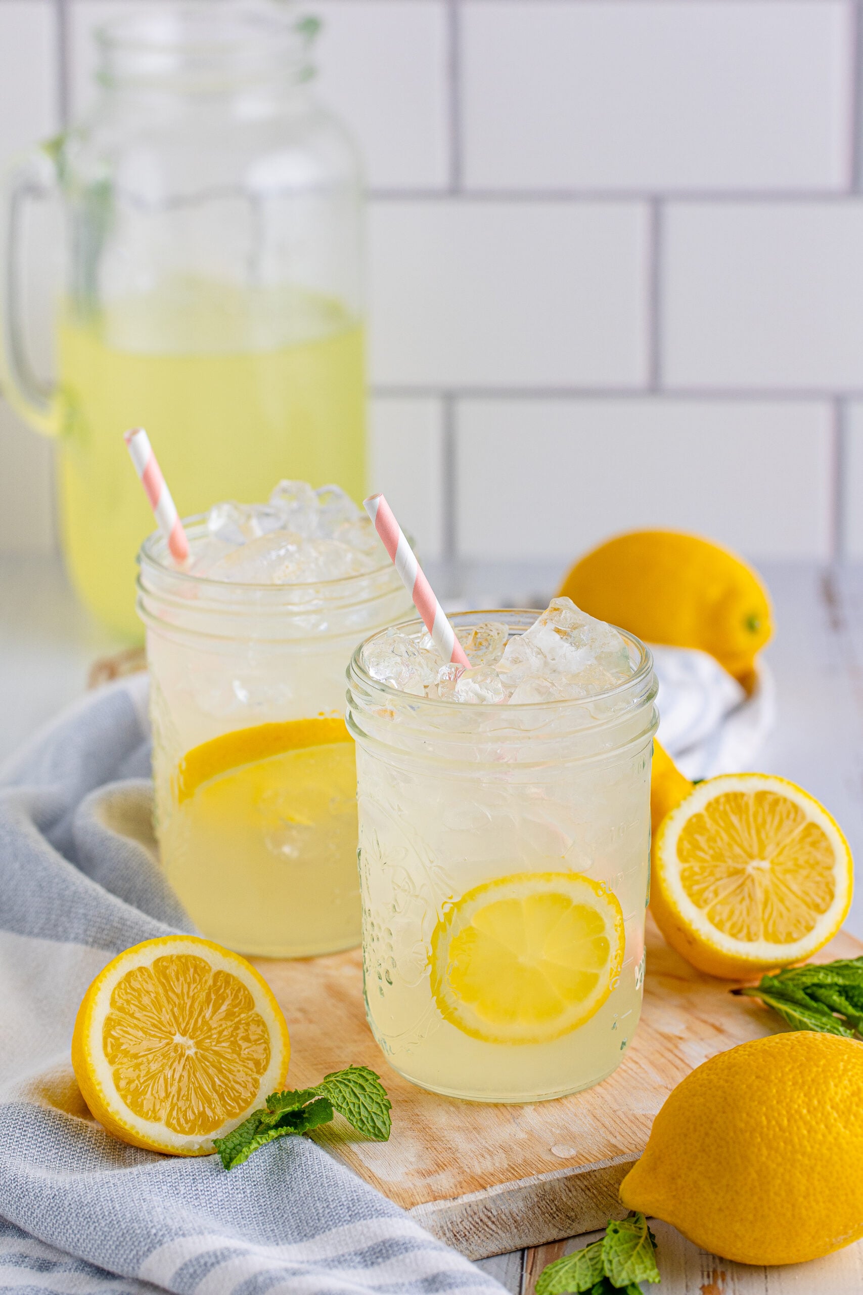 Front view of Homemade Lemonade in two mason jars garnished with lemon slices.