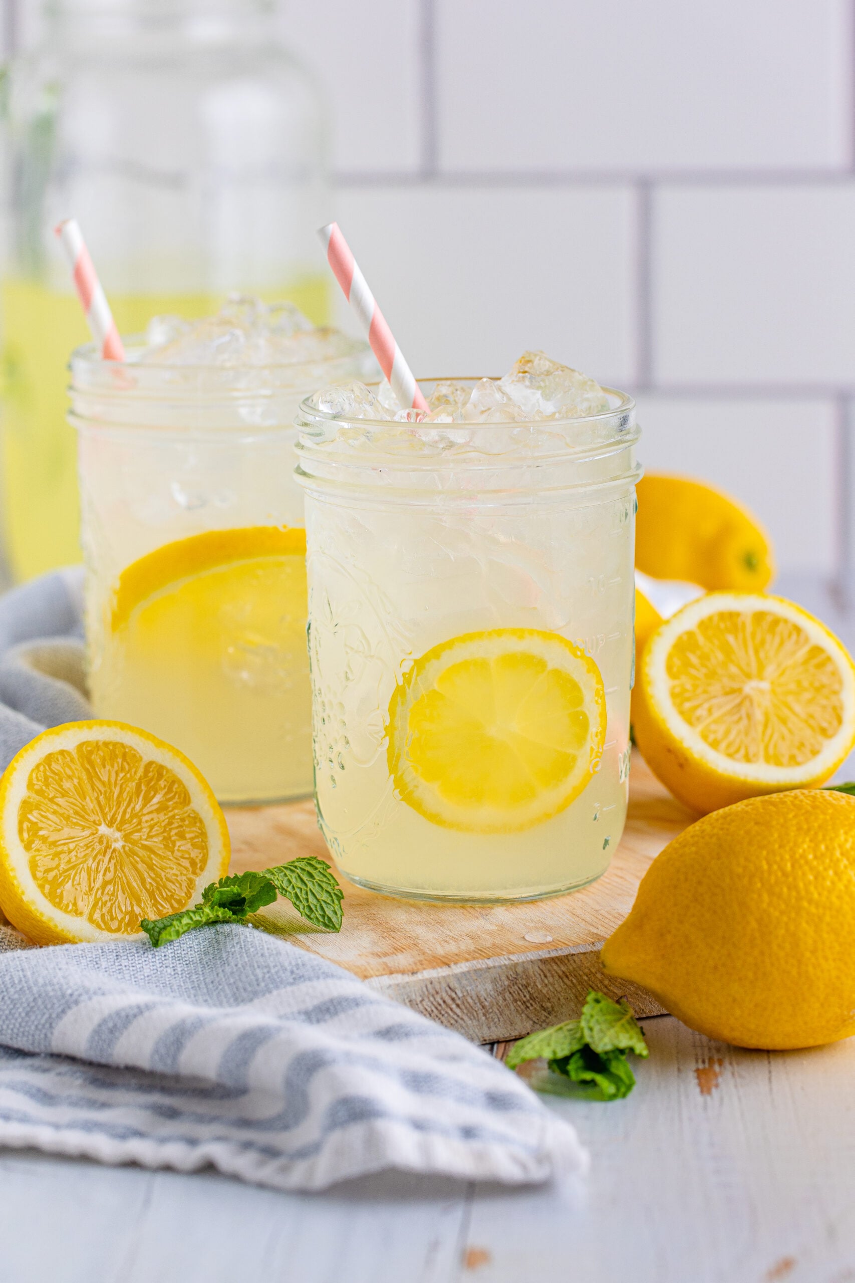 Front view of Homemade Lemonade in two mason jars garnished with lemon slices.